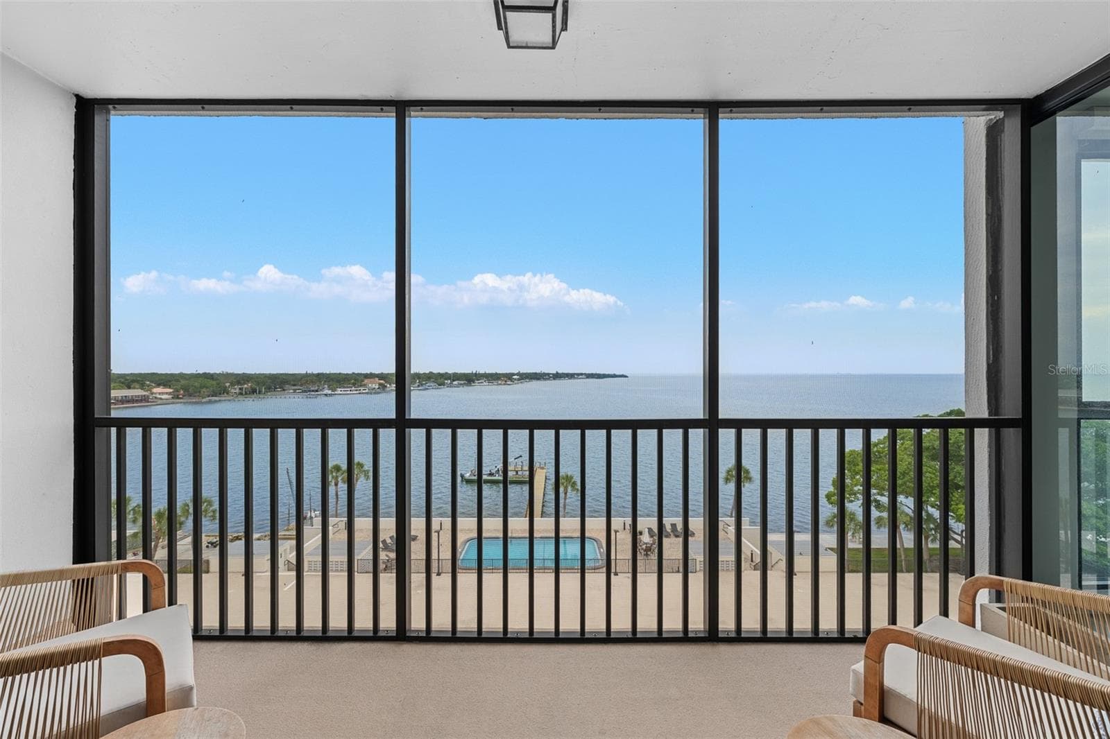 Screened terrace overlooking the bay-side heated community pool, private fishing pier, and open water of Tampa Bay. - 7100 SUNSHINE SKYWAY LN S #701, ST PETERSBURG
