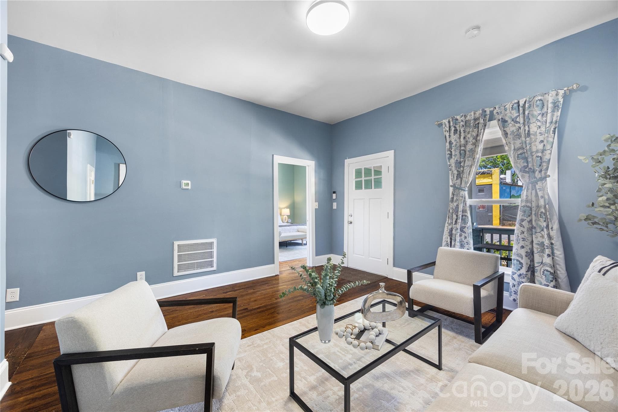 Rich hardwood flooring and dramatic ceiling height make this living room both elegant and welcoming. - Charlotte