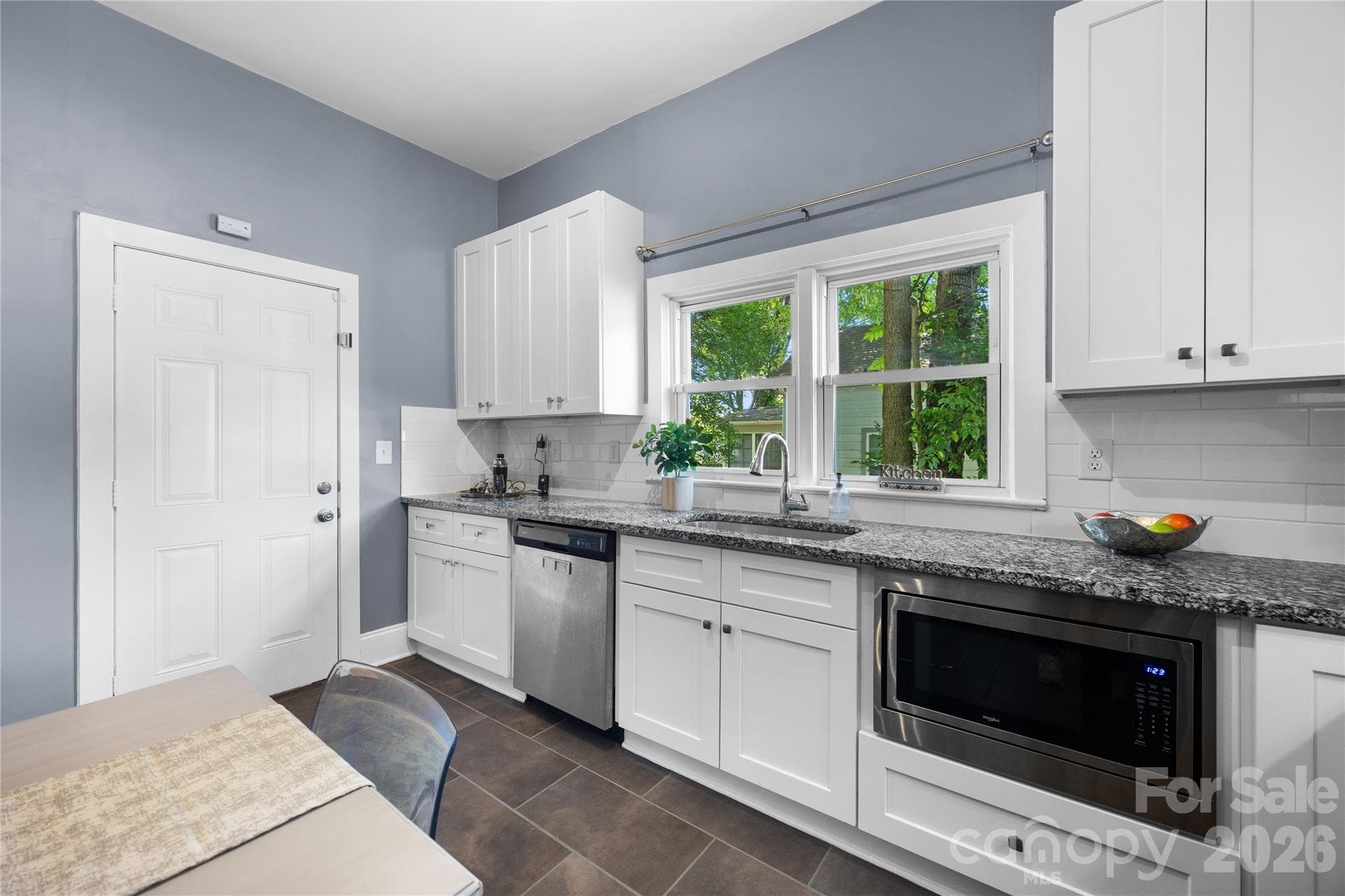 Large light-filled kitchen showcasing updated finishes, stainless steel appliances, and easy access to the backyard. - Charlotte