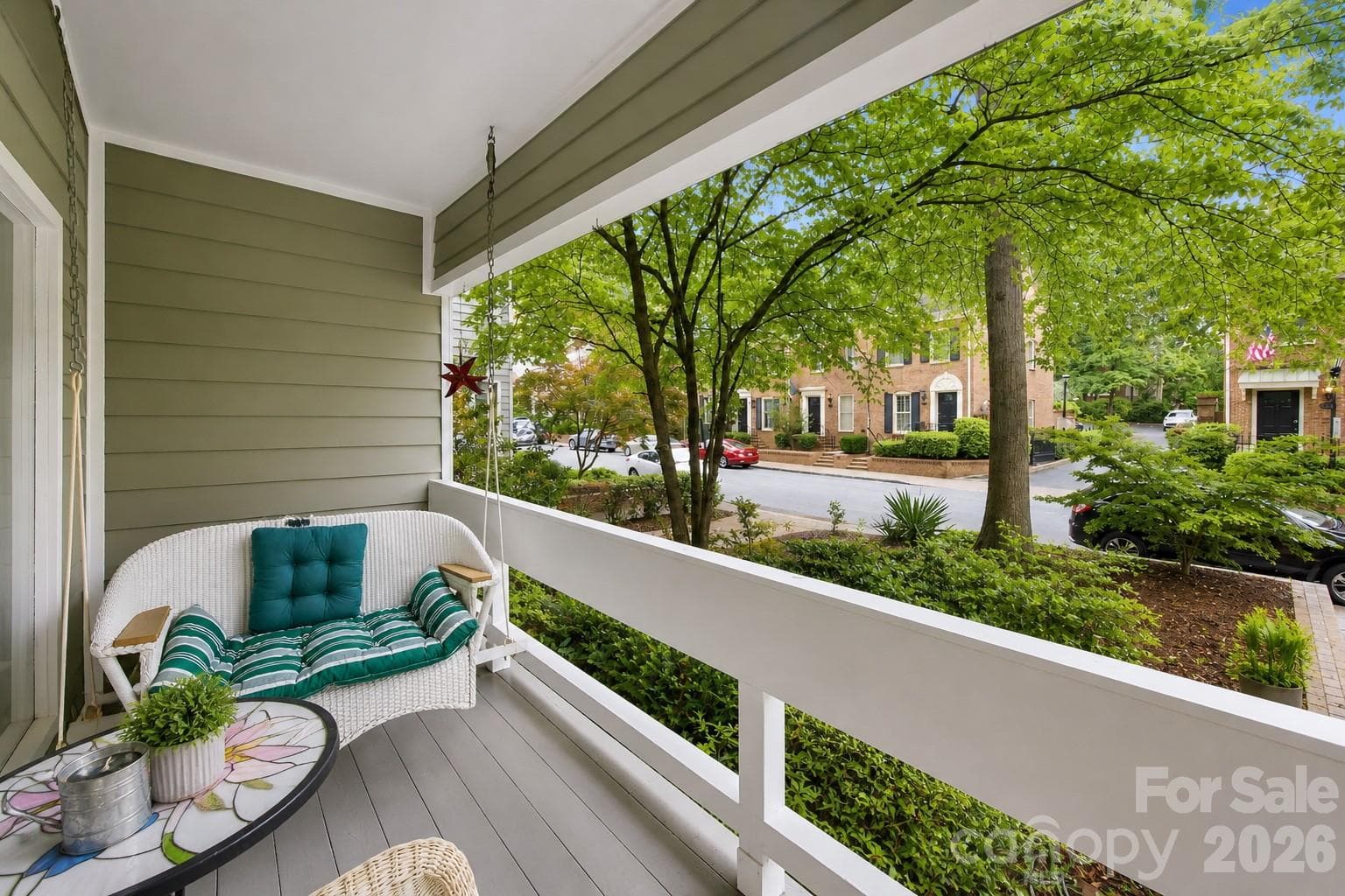 Charming covered front porch surrounded by mature trees and lush landscaping, perfect for relaxing outdoors - Charlotte