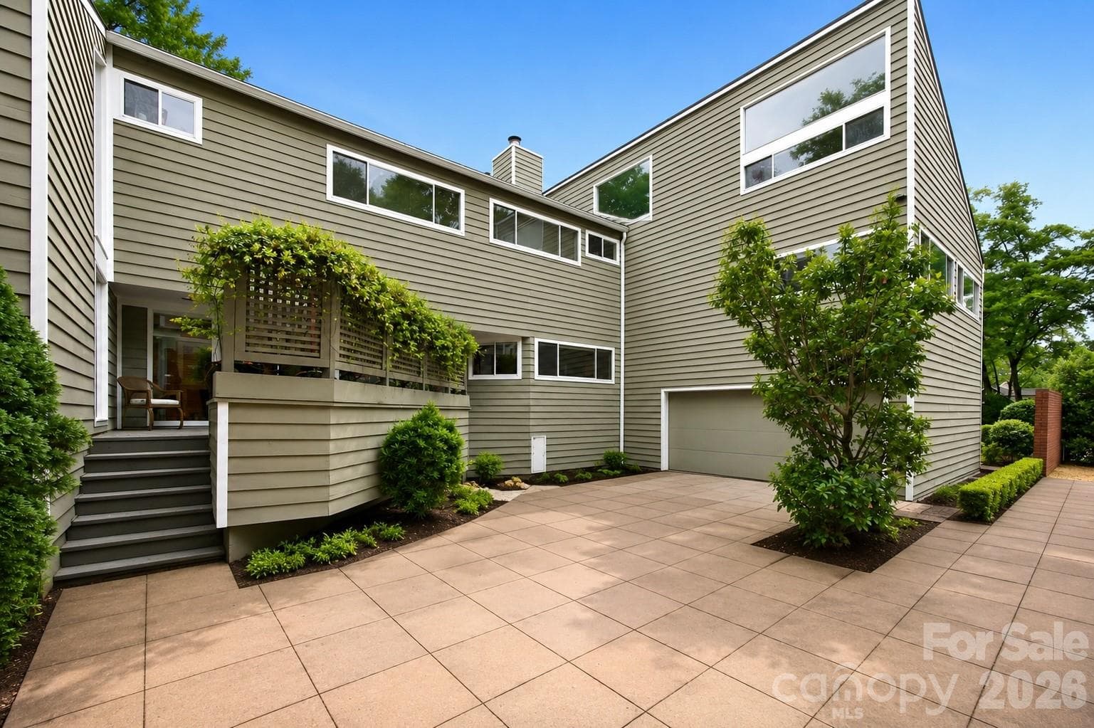 Expansive paver drive and versatile garage with front and rear-facing access for added functionality - Charlotte