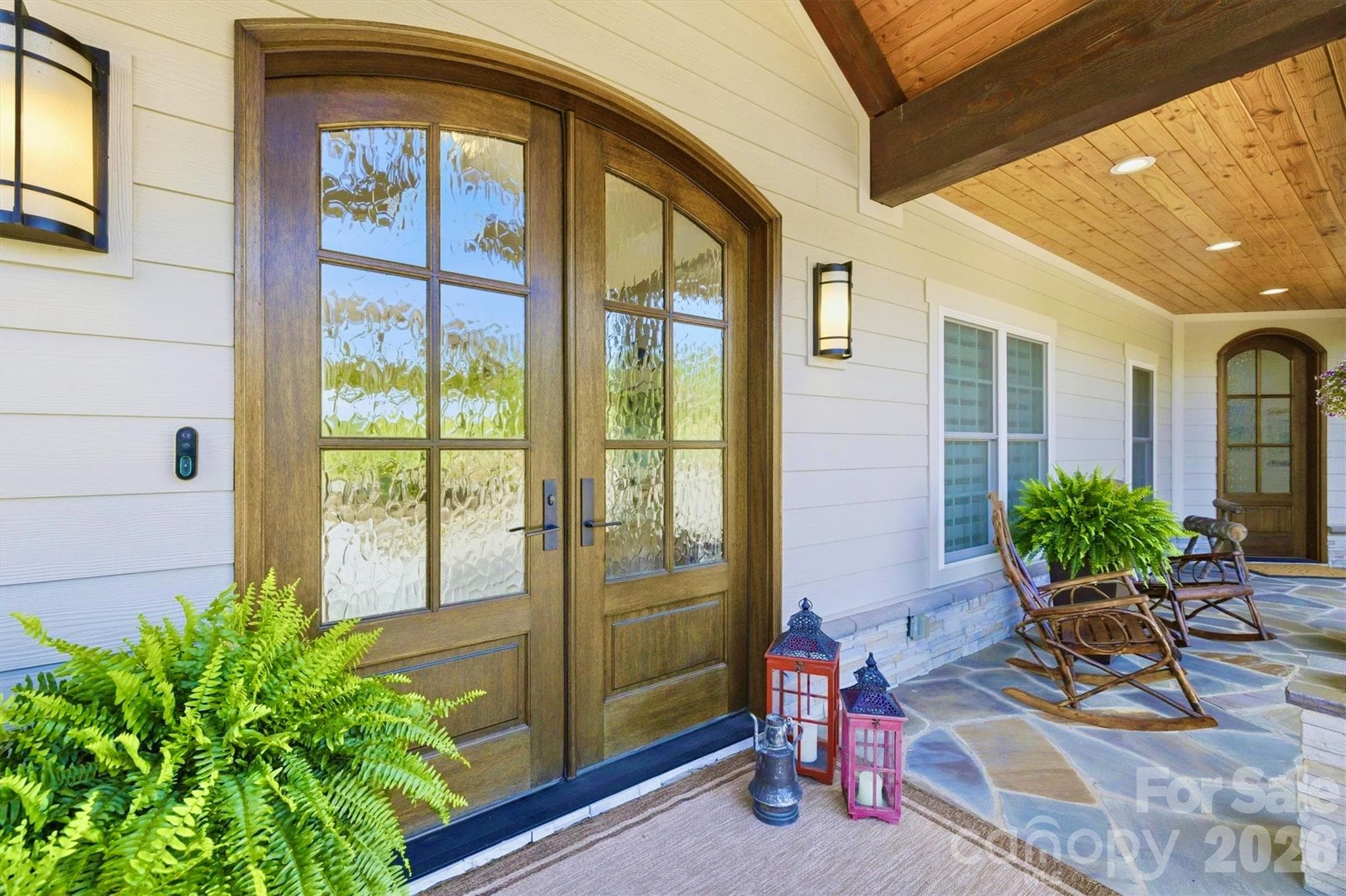 The deep flagstone front porch is a welcoming spot.    Arched double french doors with restoration glass open in to the grand foyer, illuminated by a Swarovski crystal chandelier.  The entrance on the right opens to the study. - Lenoir