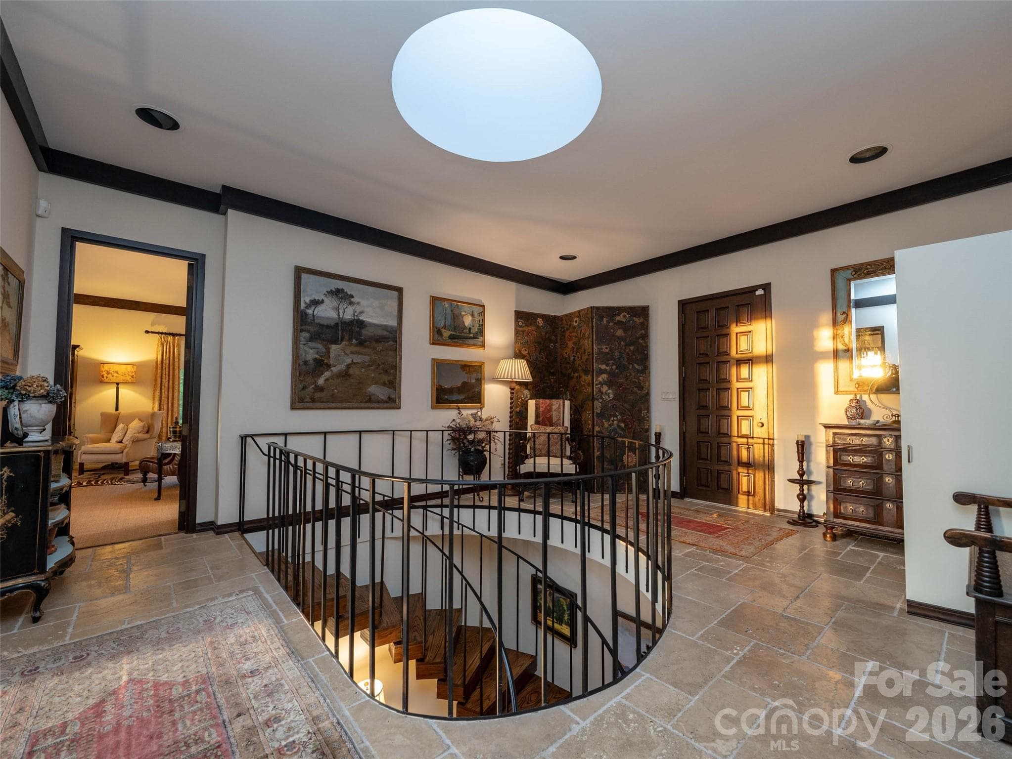 A 1970s front door embracing a piece of architectural history opens to early morning or late afternoon light from the original skylight that highlights circular staircase - Asheville