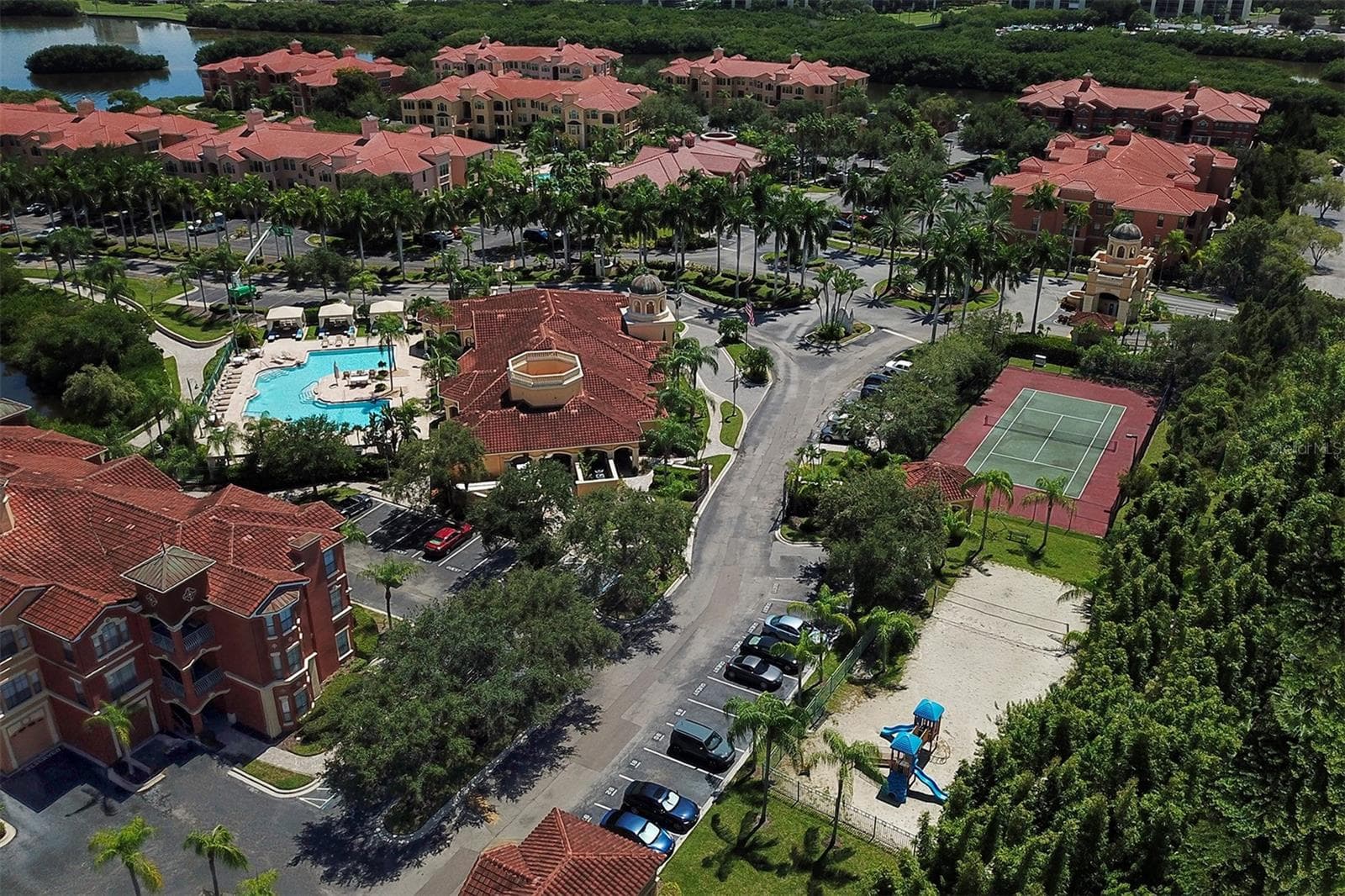 Aerial photo of the clubhouse and pool to the left, playground and sand volleyball court to the right and tennis court and guardhouse toward the top right - 2746 VIA TIVOLI #110B, CLEARWATER