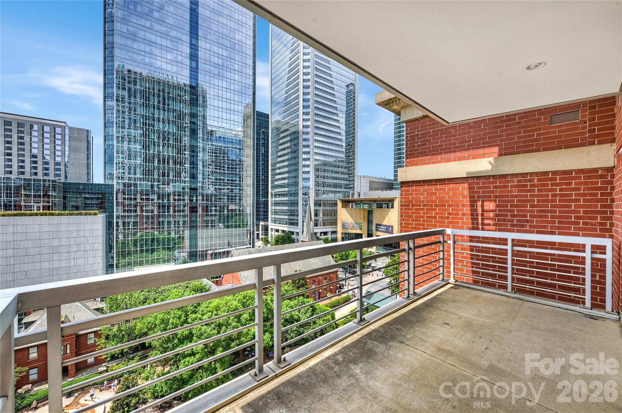 The covered terrace offers room to dine, entertain, or simply take in Uptown. The brick wall provides privacy from the neighboring unit. - 435 S Tryon Street, Charlotte