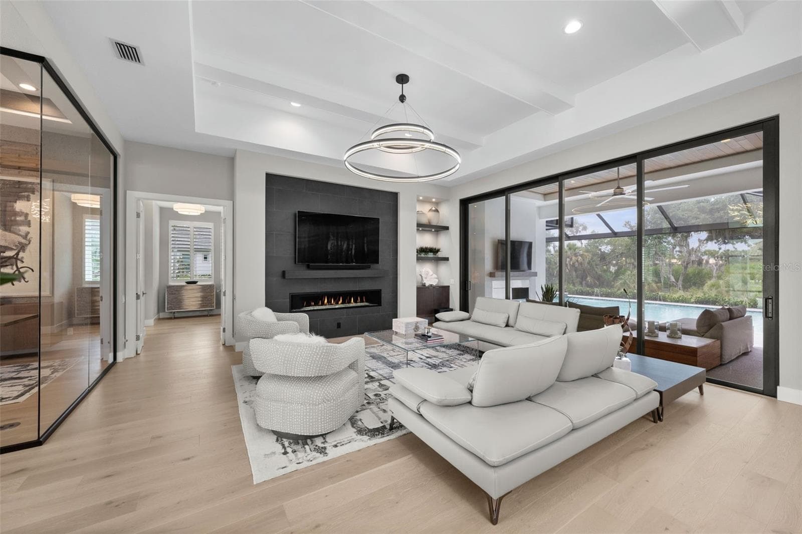 The great room is accented by wood beams, impressive chandeliers, gas fireplace, built-in cabinetry and oversized sliding glass doors that seamlessly connect indoor and outdoor living spaces. - 11721 RIVE ISLE RUN, PARRISH