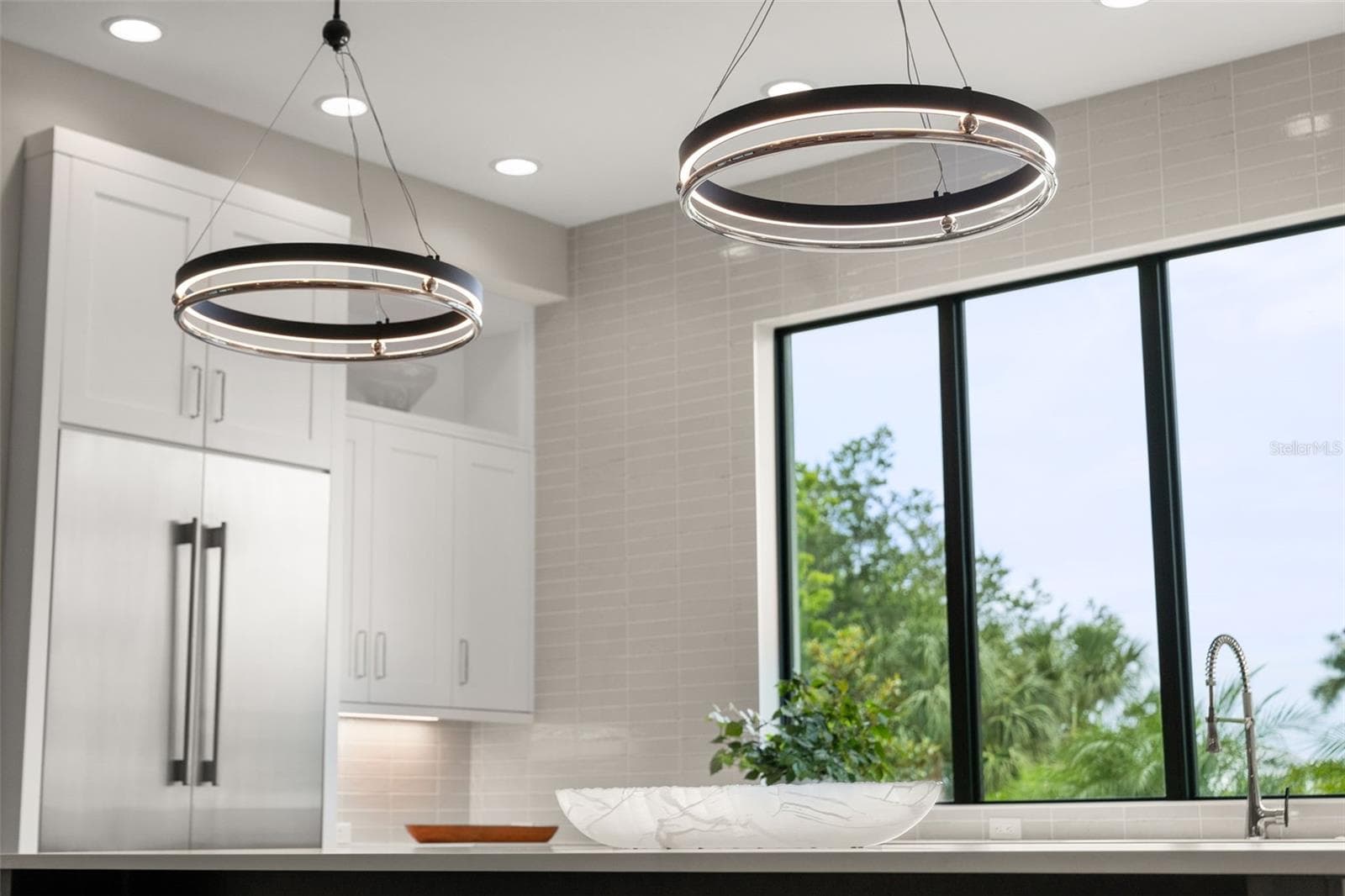 Two Metropolitan Grande Illusion LED Pendants hang above the island. - 11721 RIVE ISLE RUN, PARRISH
