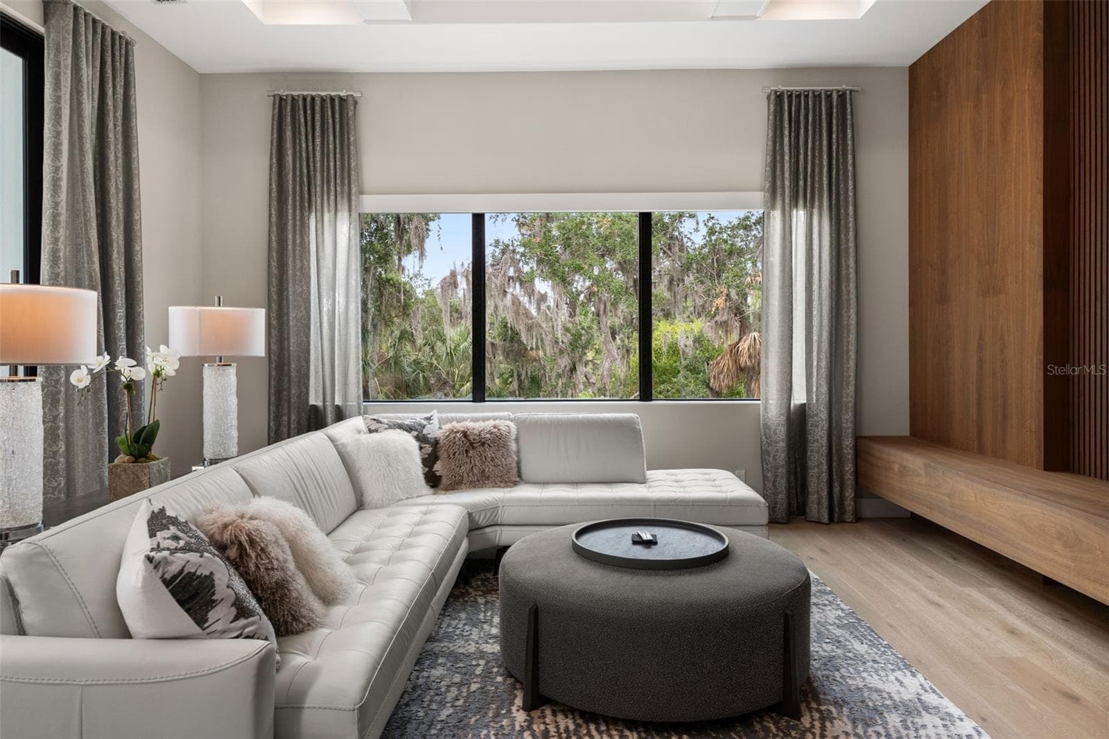 This exceptional space features a custom wood accent wall, oversized windows with tropical forest views, electric shades, direct sliding glass door access to the pool and lanai. - 11721 RIVE ISLE RUN, PARRISH