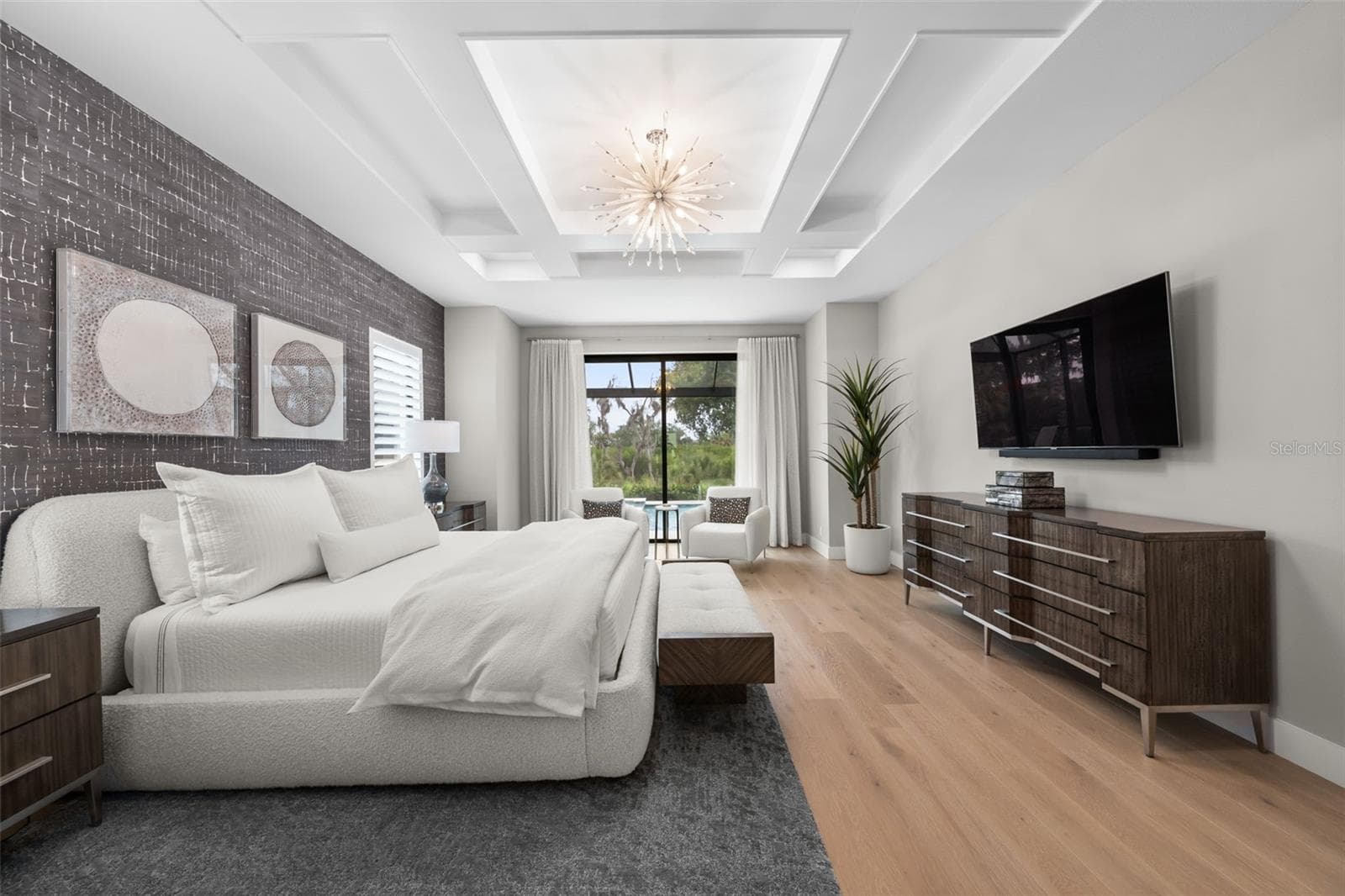 The owner’s suite serves as a luxurious private retreat, thoughtfully designed to capture peaceful views and provide seamless access to the outdoor living areas through expansive sliding glass doors opening directly to the lanai, pool, and spa. - 11721 RIVE ISLE RUN, PARRISH
