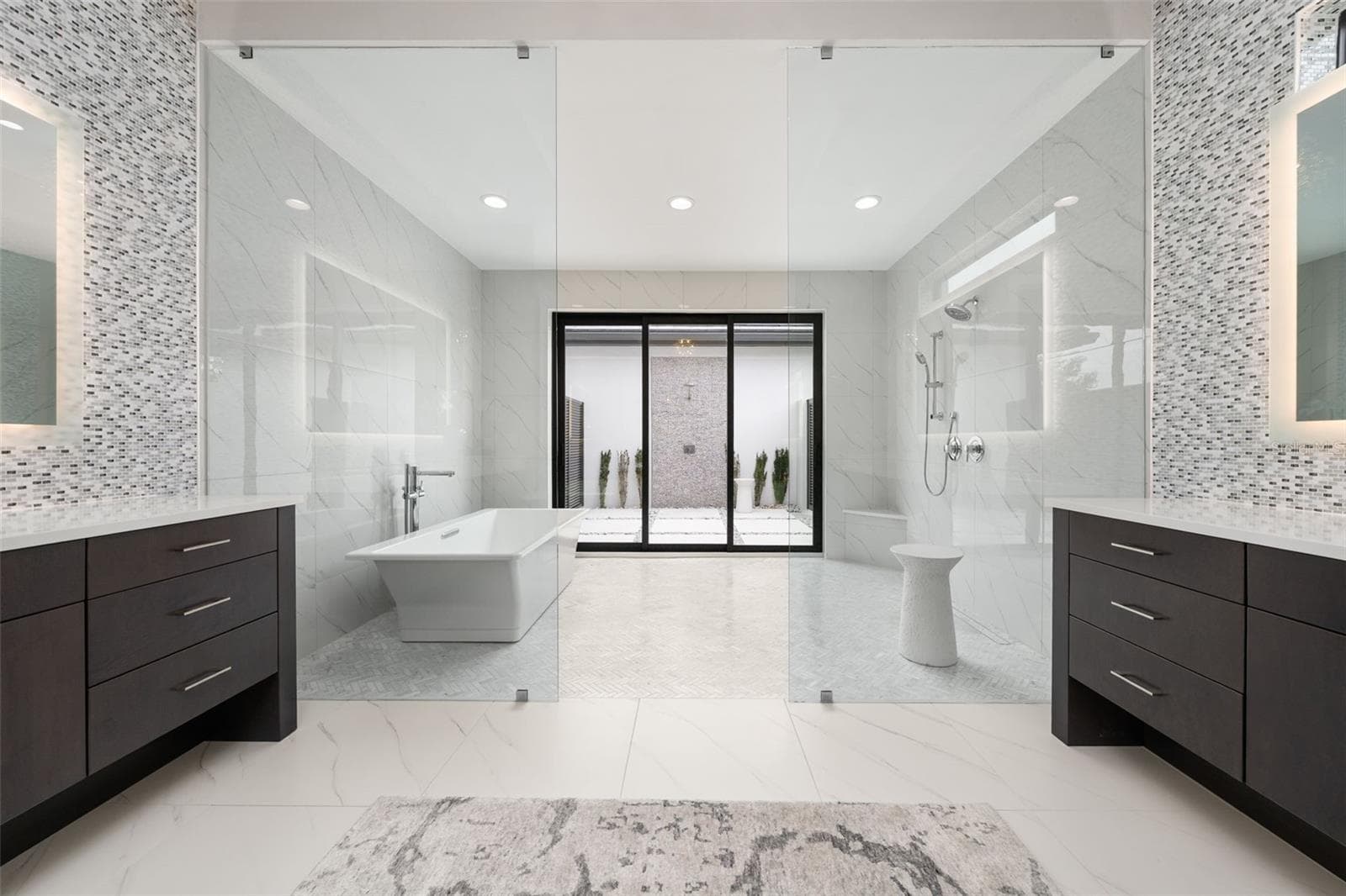 The oversized walk-in shower with floor-to-ceiling tile and dual showerheads has sliding glass door leading to an outdoor shower and private patio. - 11721 RIVE ISLE RUN, PARRISH