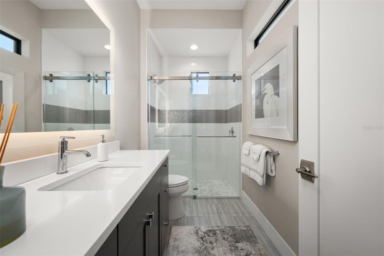 The bathroom has a large vanity, backlit mirror and walk-in shower with glass shower door. - 11721 RIVE ISLE RUN, PARRISH