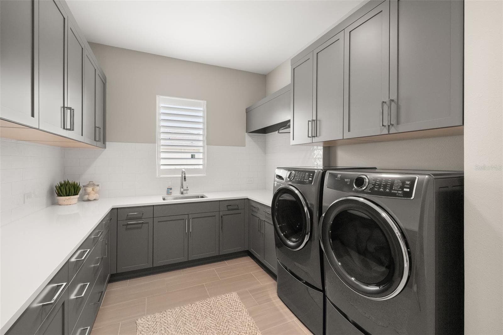 Even the laundry room has been elevated to designer quality with custom wood cabinetry, quartz countertops, tile backsplash, sink with views overlooking the landscaped yard, dual storage closets with custom shelving, and pedestal Electrolux washer and dryer systems. - 11721 RIVE ISLE RUN, PARRISH