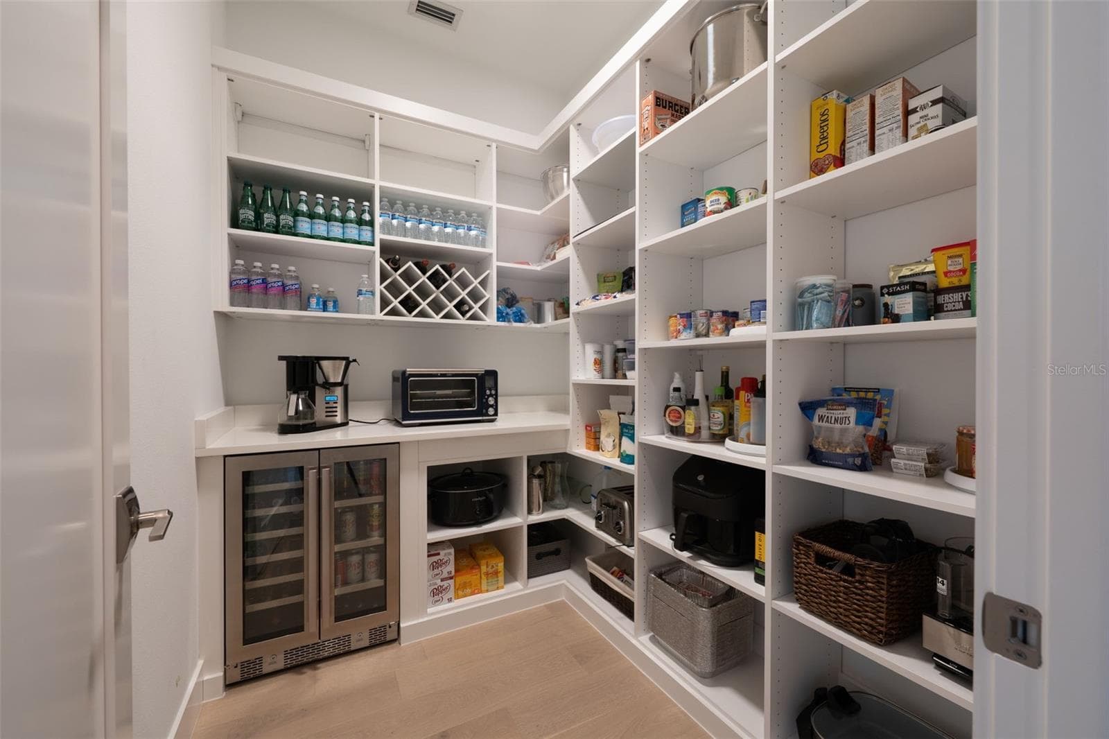 Adjacent to the kitchen, a walk-in pantry offers additional luxury and convenience with custom shelving, beverage refrigerator, and electrical outlets ideal for small appliances and storage. - 11721 RIVE ISLE RUN, PARRISH
