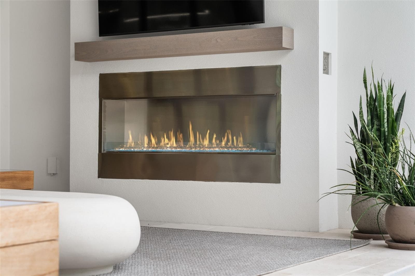 A dramatic gas fireplace with glass rocks and accent lighting create an atmosphere that feels both luxurious and inviting. - 11721 RIVE ISLE RUN, PARRISH