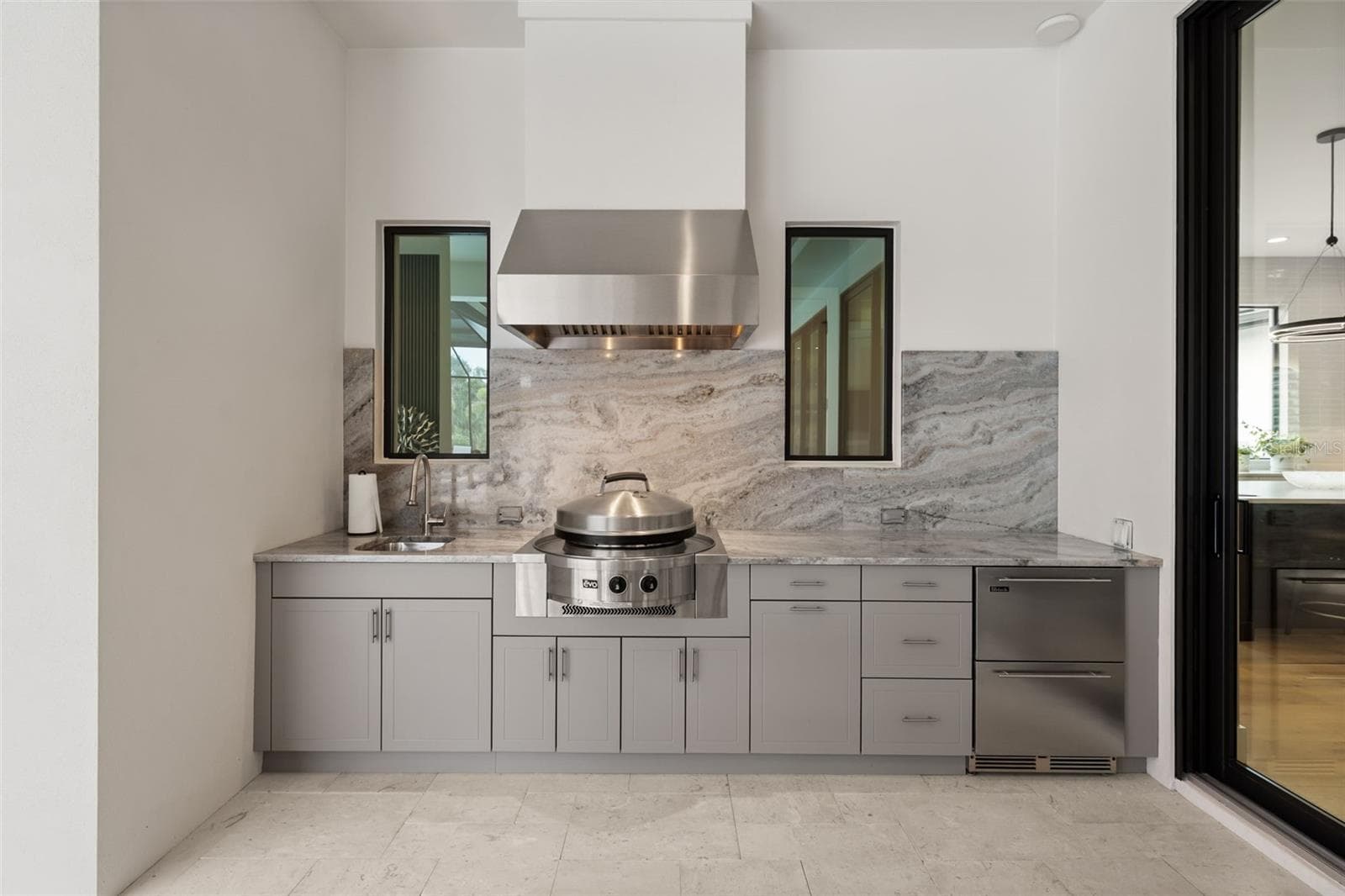 The fully equipped outdoor kitchen rivals the interior kitchen in both style and function, featuring an Evo gas grill, sink, dual Perlick refrigerator drawers, custom outdoor cabinetry with integrated trash storage, granite countertops and backsplash. - 11721 RIVE ISLE RUN, PARRISH