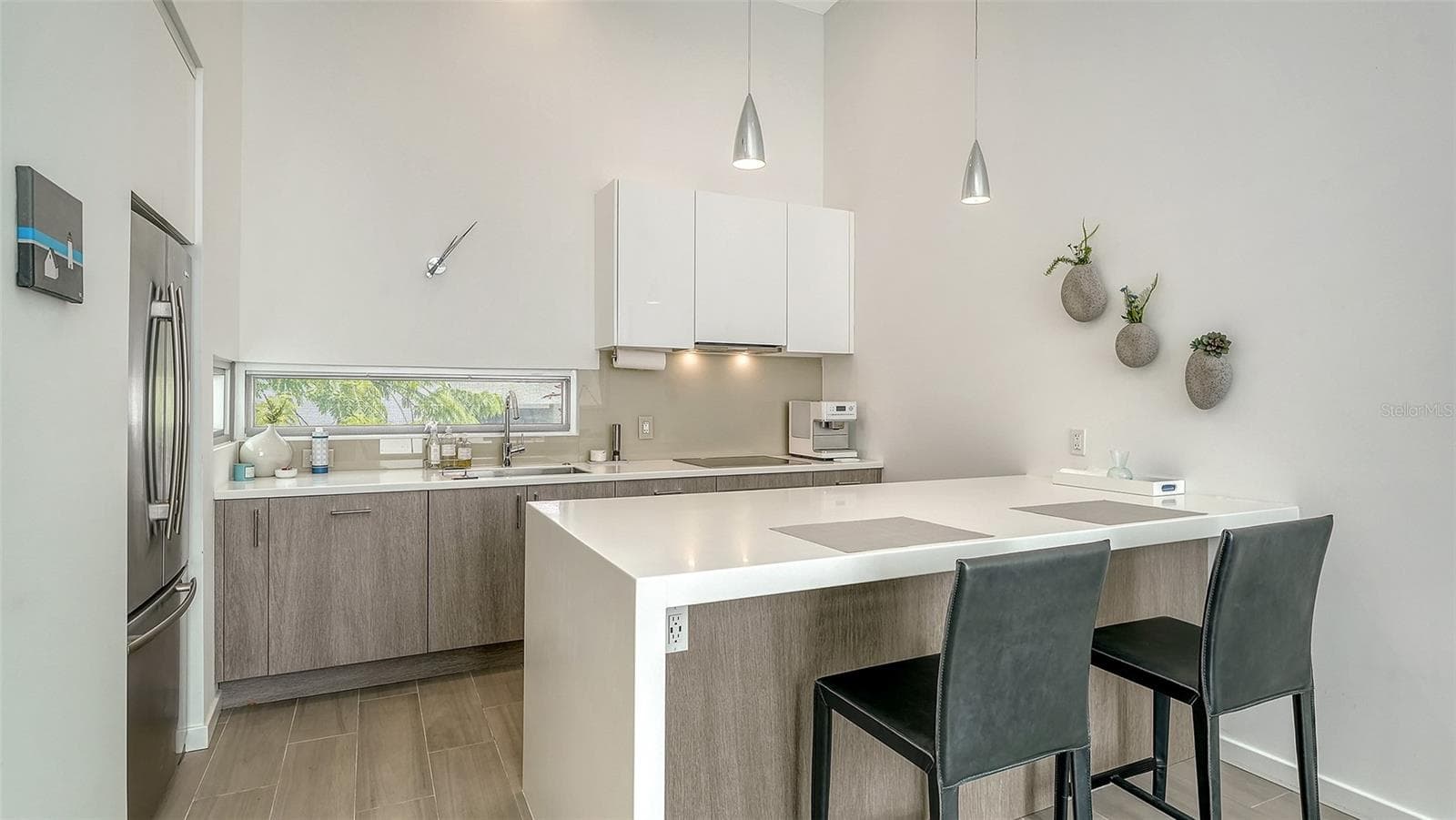 Contemporary kitchen with solid surface countertops and waterfall-edge island and SS appliances, including Miele induction range & Miele d/w, hood, and oven/microwave - 1350 5TH STREET #106, SARASOTA