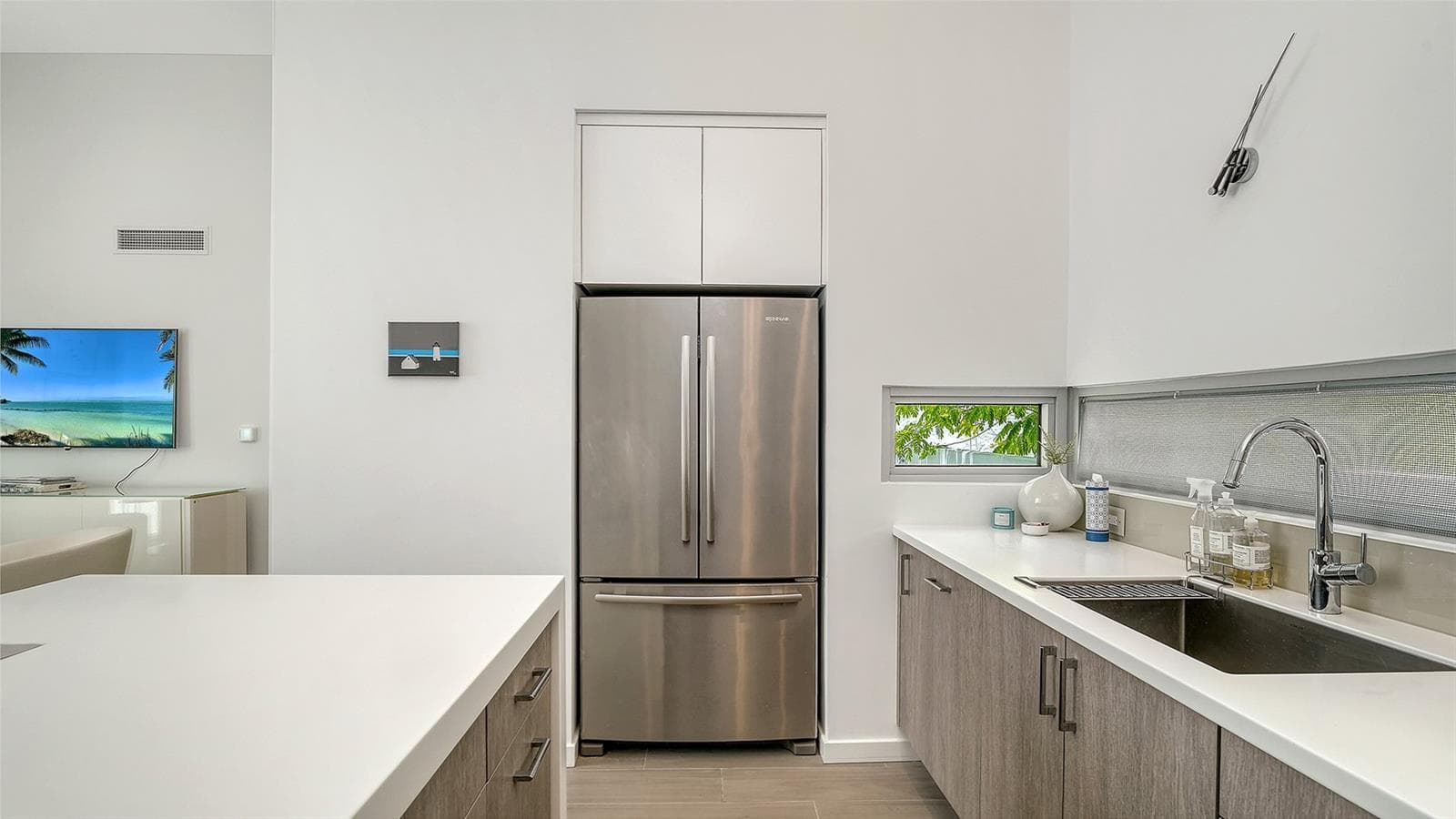 Contemporary kitchen with solid surface countertops and waterfall-edge island and SS appliances, including Miele induction range & Miele d/w, hood, and oven/microwave. - 1350 5TH STREET #106, SARASOTA