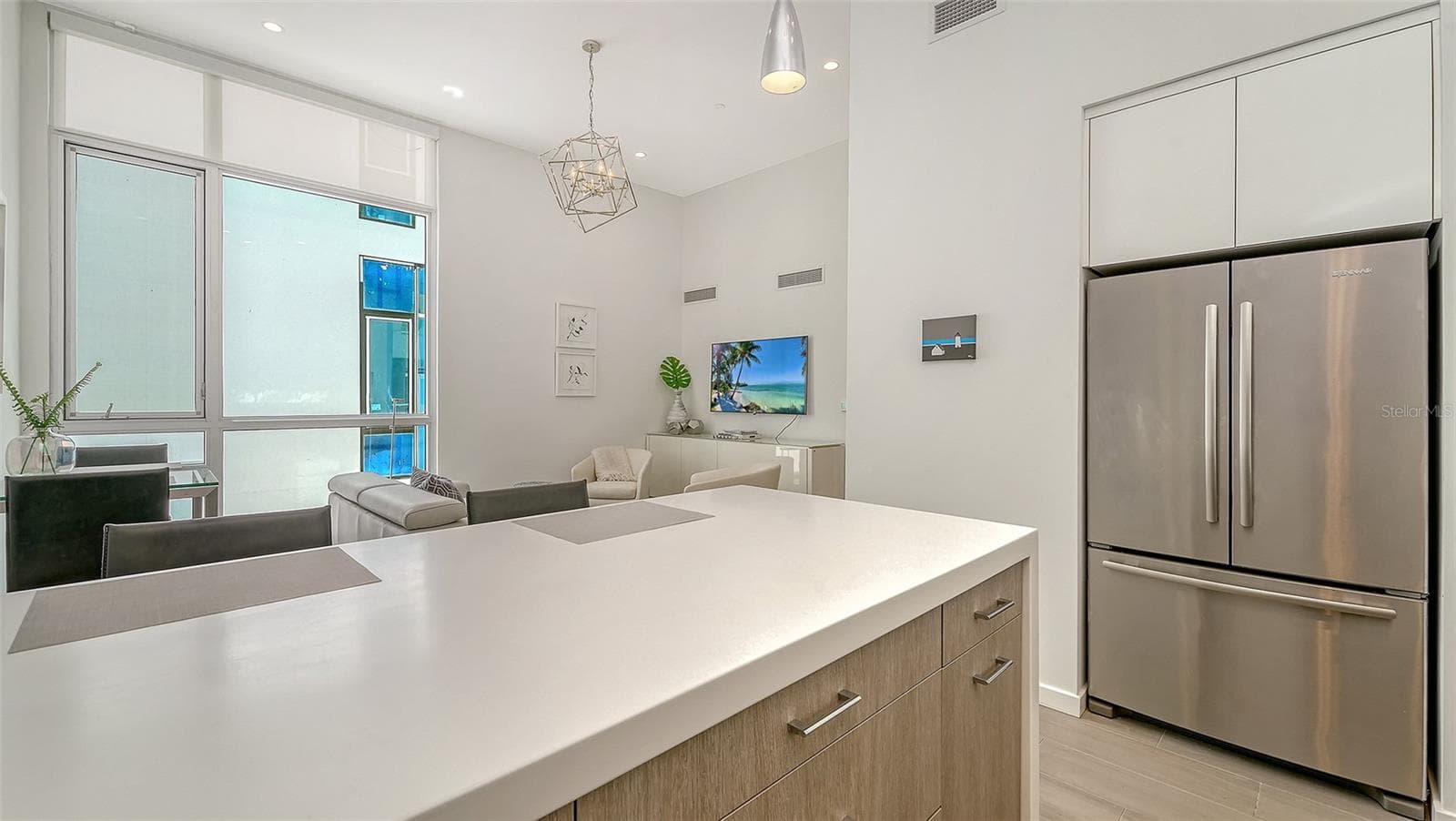 Contemporary kitchen with solid surface countertops and waterfall-edge island and SS appliances, including Miele induction range & Miele d/w, hood, and oven/microwave. - 1350 5TH STREET #106, SARASOTA