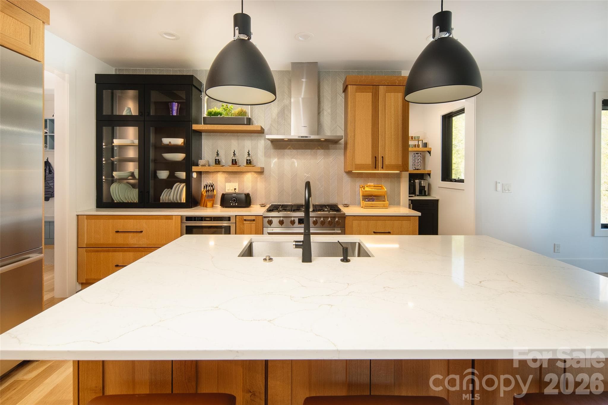 Chef's kitchen with custom black and white rift oak cabinets, premium appliances, and massive island. - Asheville