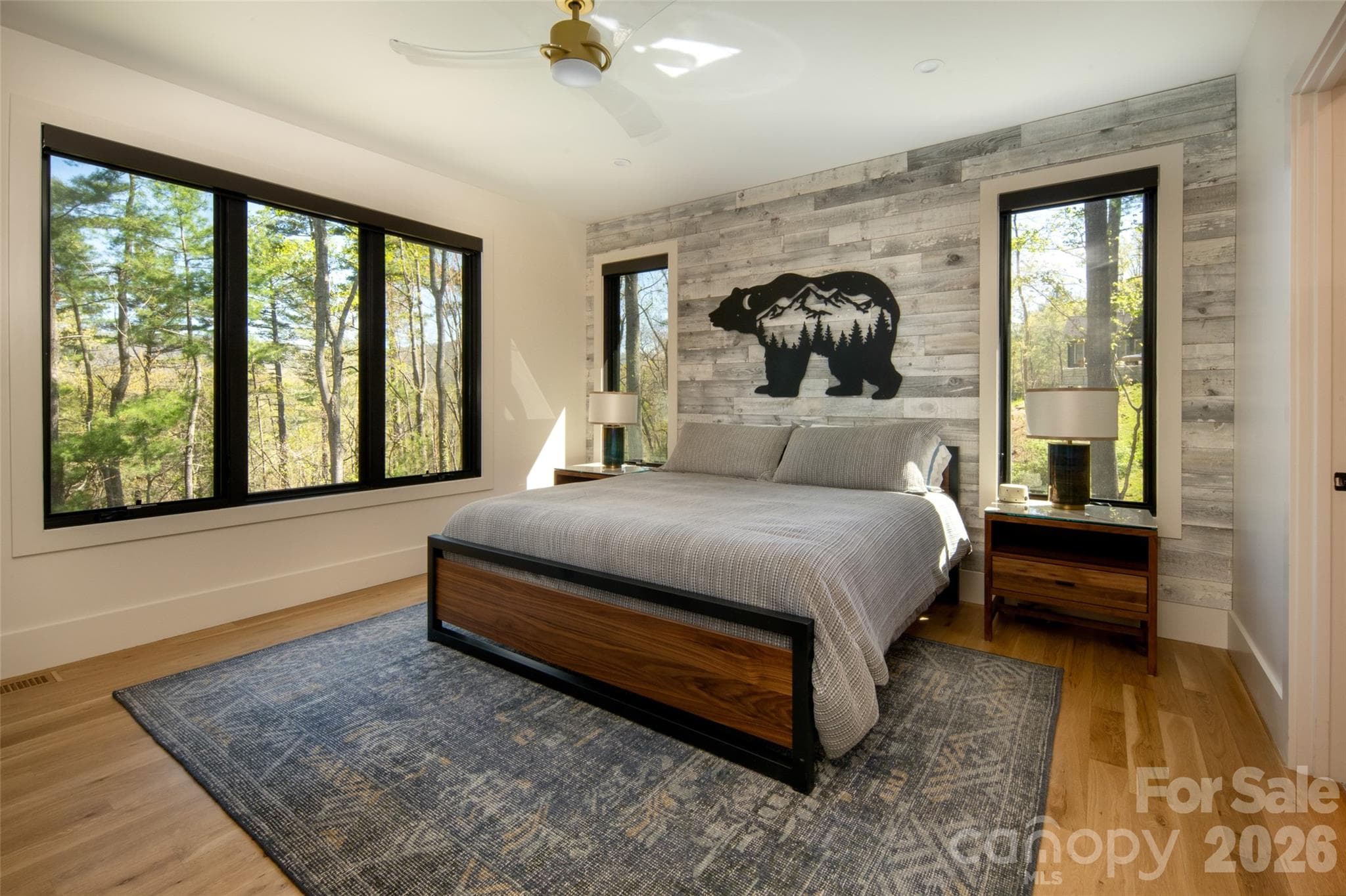 First of two large primary ensuite bedrooms with tons of natural light, gorgeous hardwood floors, wood accent wall, stunning views and remote-controlled motorized Smith & Noble solar shades (motorized shades in ALL bedrooms). - Asheville