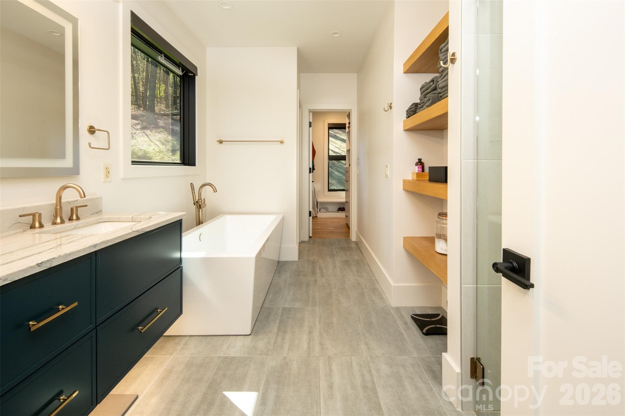 Primary ensuite bath with soaking tub, separate stand-up shower, floating double vanity with LED-lighted vanity mirror. Bath leads to massive walk-in/wrap-around closet and adjoining laundry with washer/dryer and more storage. - Asheville