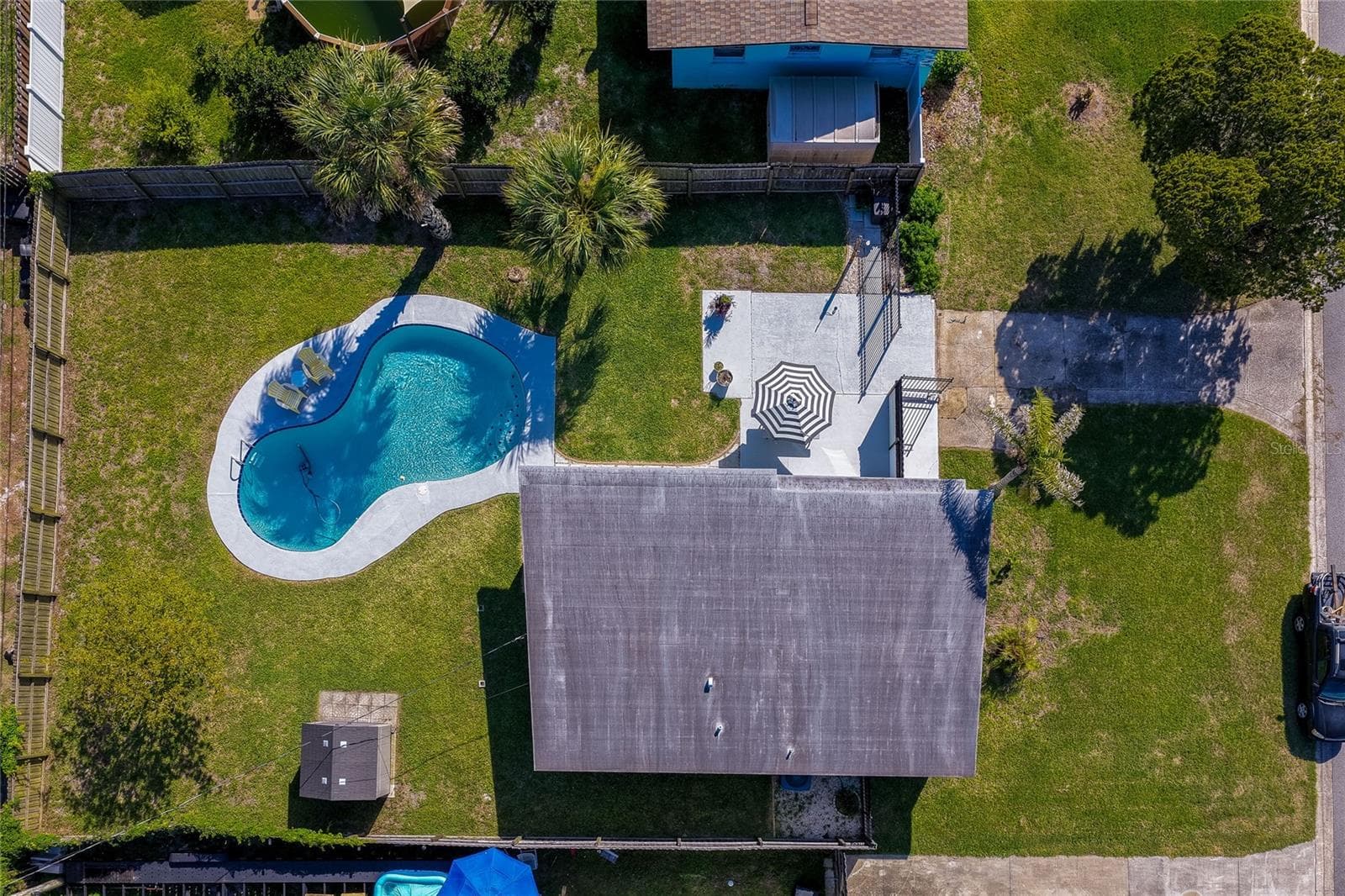 Direct top-down aerial view detailing the property's layout, including the home’s roof, a paved patio with a seating area, an immaculate lawn, and a swimming pool. - 723 STEELE AVE, SOUTH DAYTONA