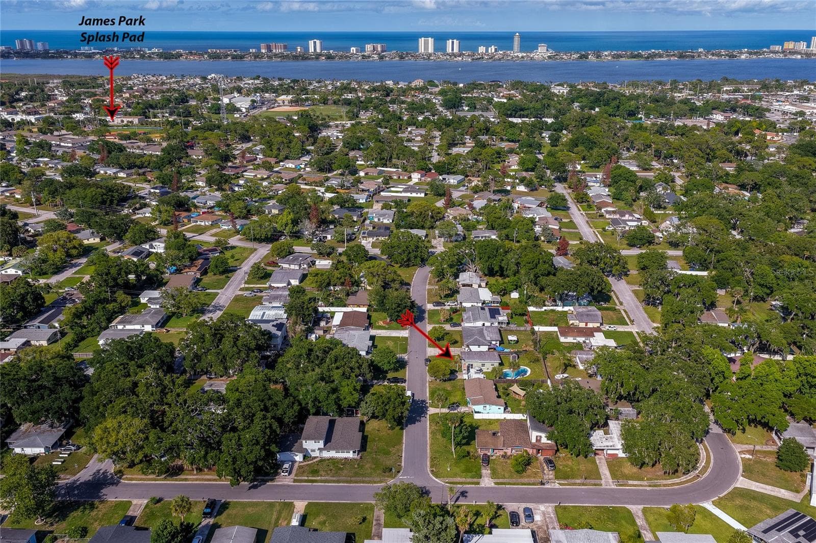 Wide aerial perspective highlighting the property’s location within the neighborhood, with a red arrow pointing toward the home and another local attractions and nearby coastal waters. - 723 STEELE AVE, SOUTH DAYTONA