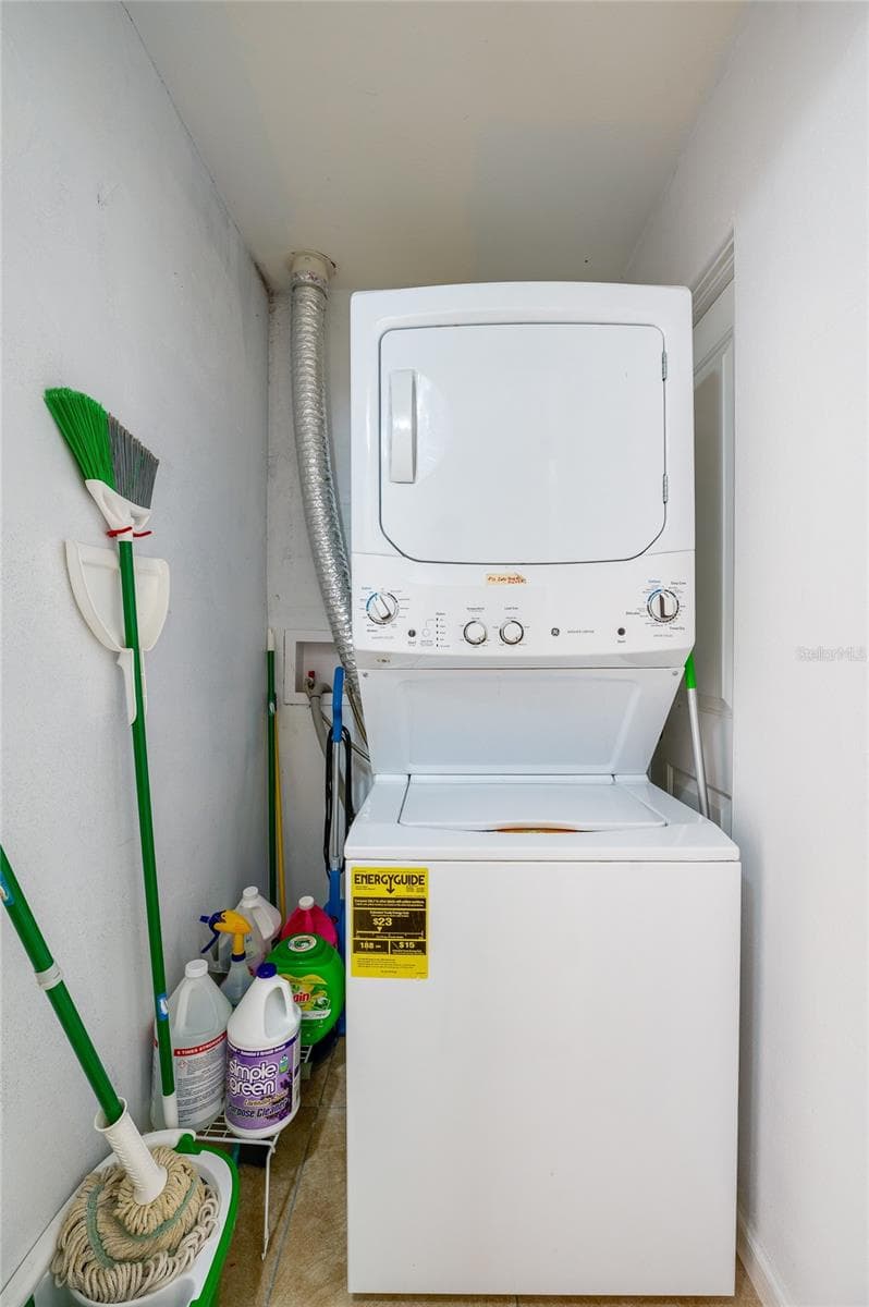 Convenient laundry niche utilizing a space-saving stacked washer and dryer unit alongside dedicated storage for household cleaning supplies. - 723 STEELE AVE, SOUTH DAYTONA