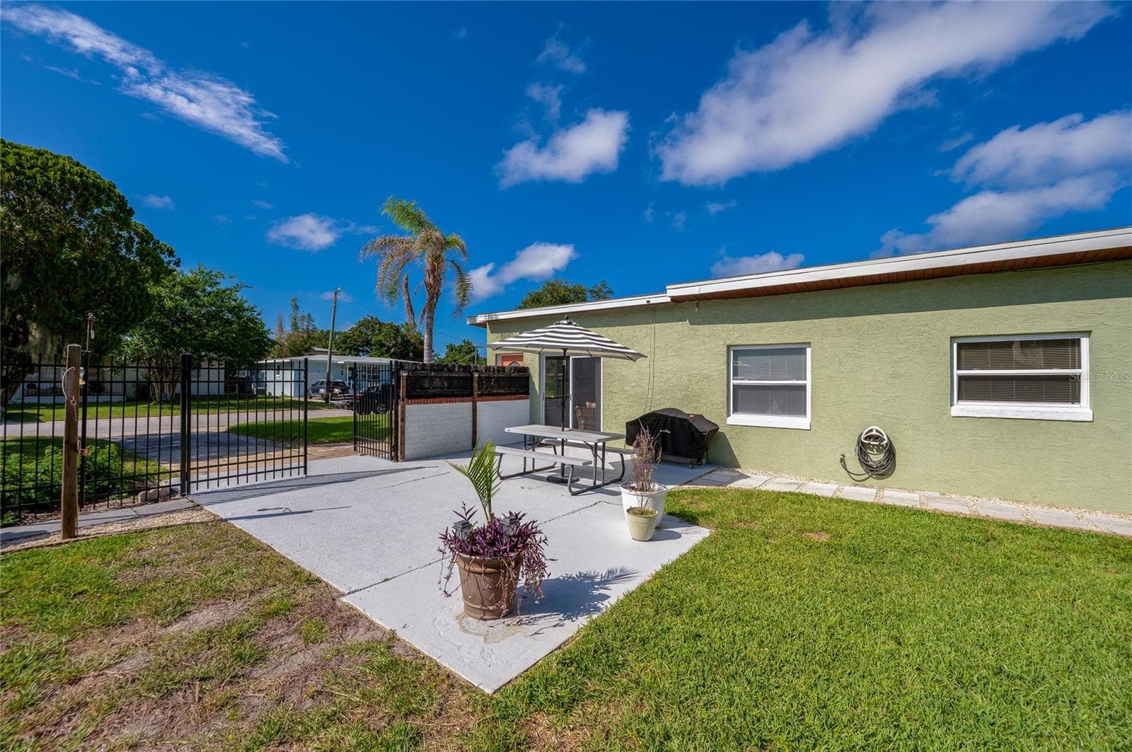 Fenced-in backyard highlighting a secure gated entry and low-maintenance green spaces. - 723 STEELE AVE, SOUTH DAYTONA