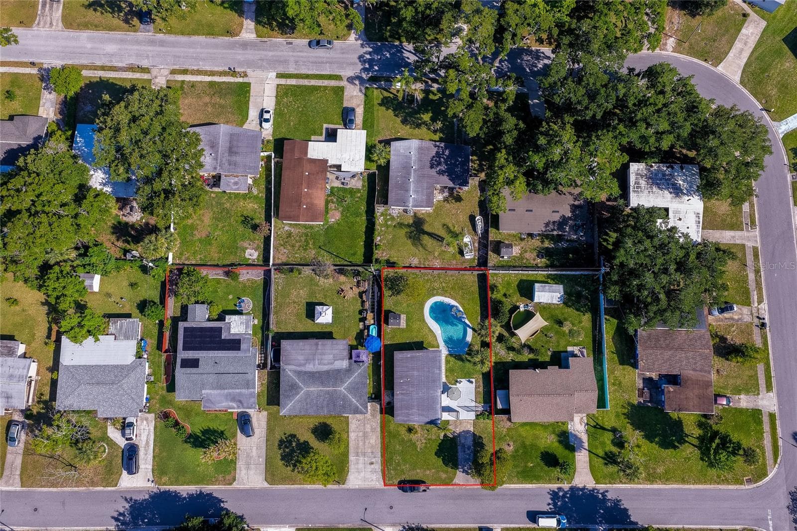 Top-down lot aerial outlined in red, clearly defining the property boundaries, spacious yard layout, and pool placement relative to surrounding neighbors. - 723 STEELE AVE, SOUTH DAYTONA