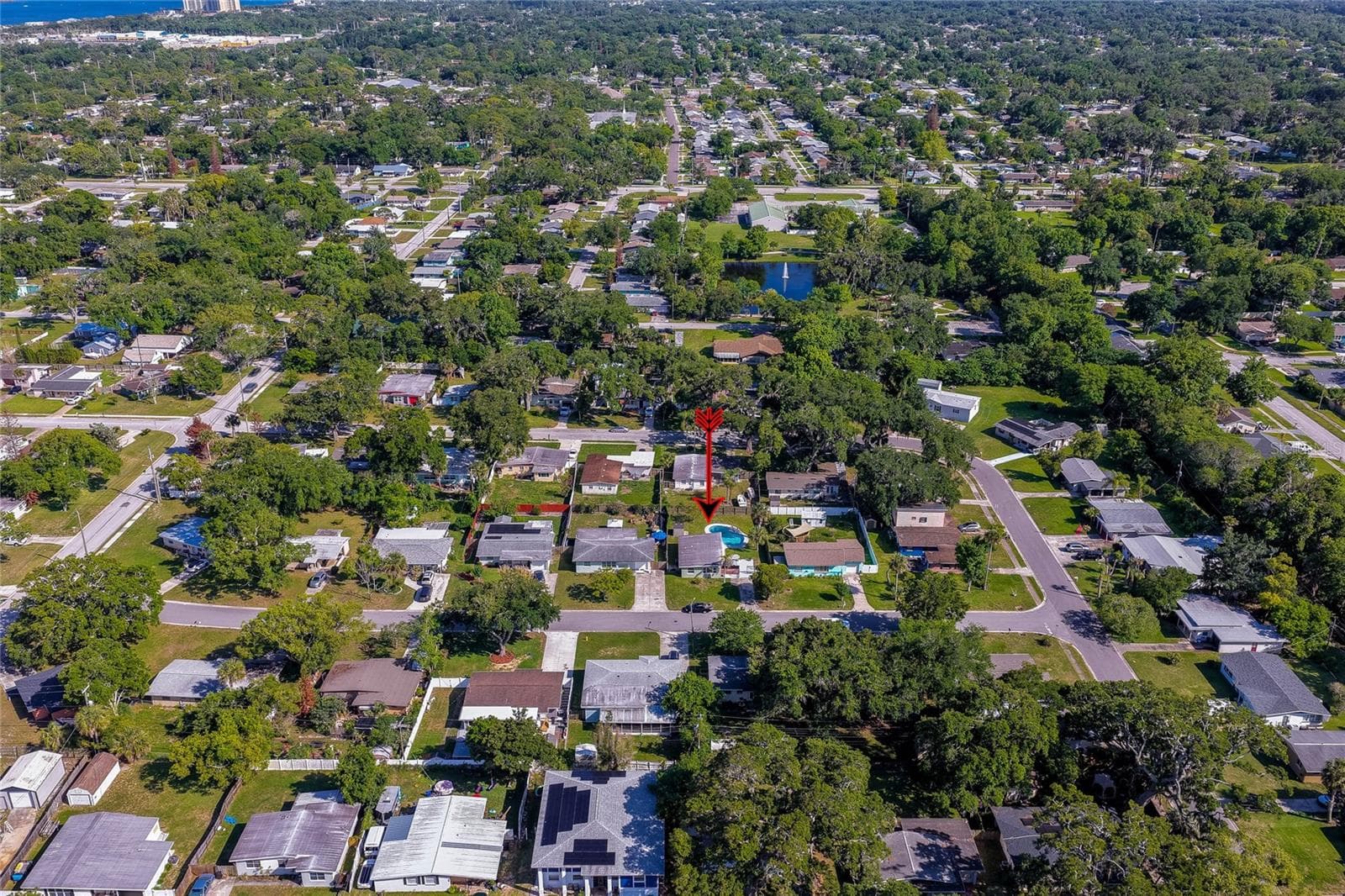 High-altitude aerial view marked with a red arrow, illustrating the property's central location within a lush, tree-lined residential community. - 723 STEELE AVE, SOUTH DAYTONA