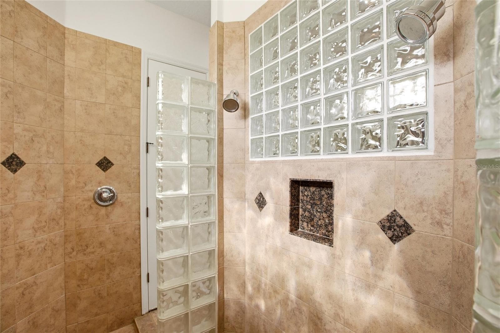 The primary bathroom features a soaking tub, split vanities with dedicated makeup counter space, a spacious walk-in shower with dual shower heads, a private water closet, and dual walk-in closets with custom organization. - 8417 LONE EAGLE WAY, SARASOTA