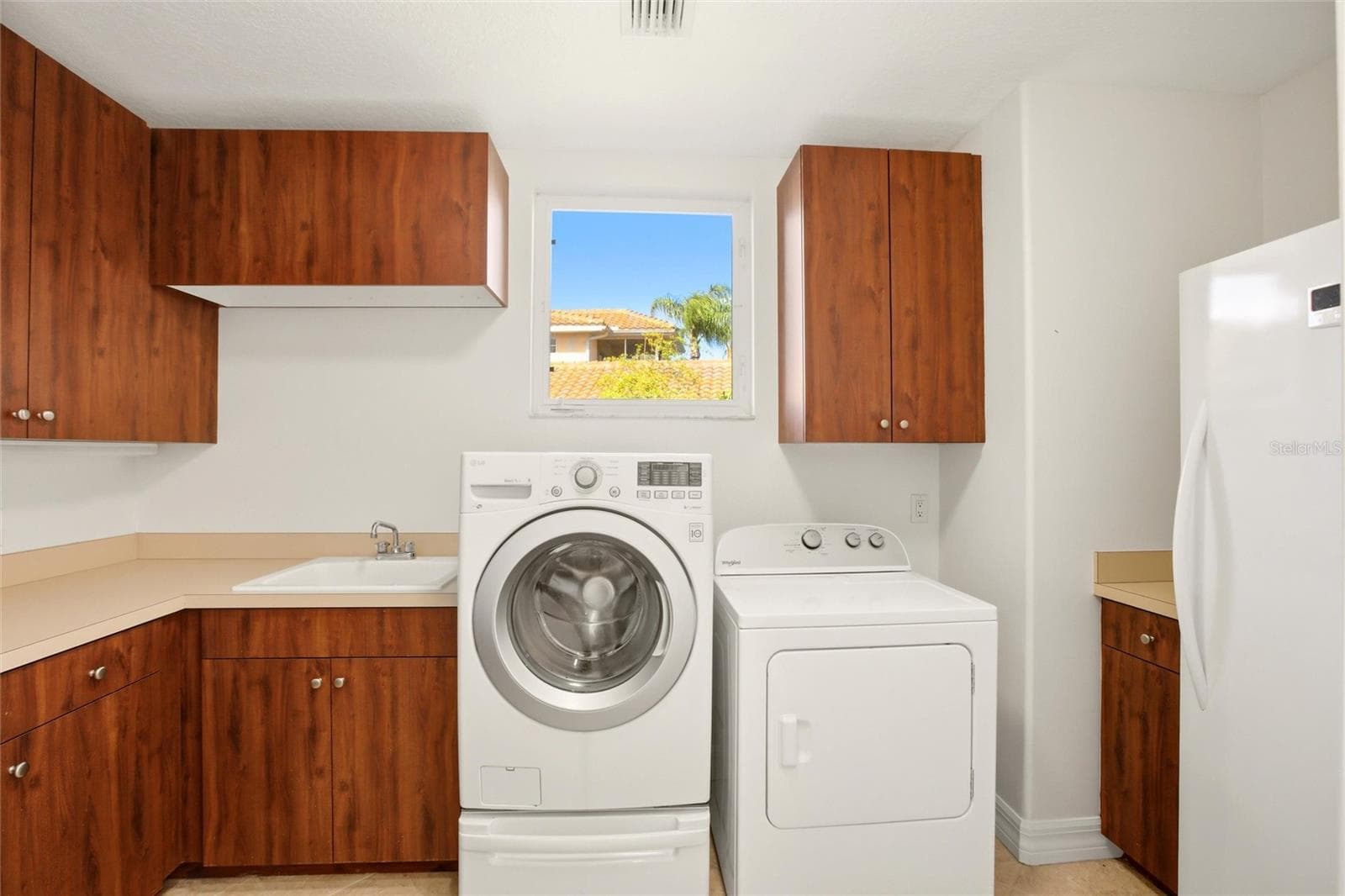 The first-floor laundry room offers abundant cabinetry, a generous folding counter workspace, and a stand-up deep freezer for added convenience and storage. - 8417 LONE EAGLE WAY, SARASOTA