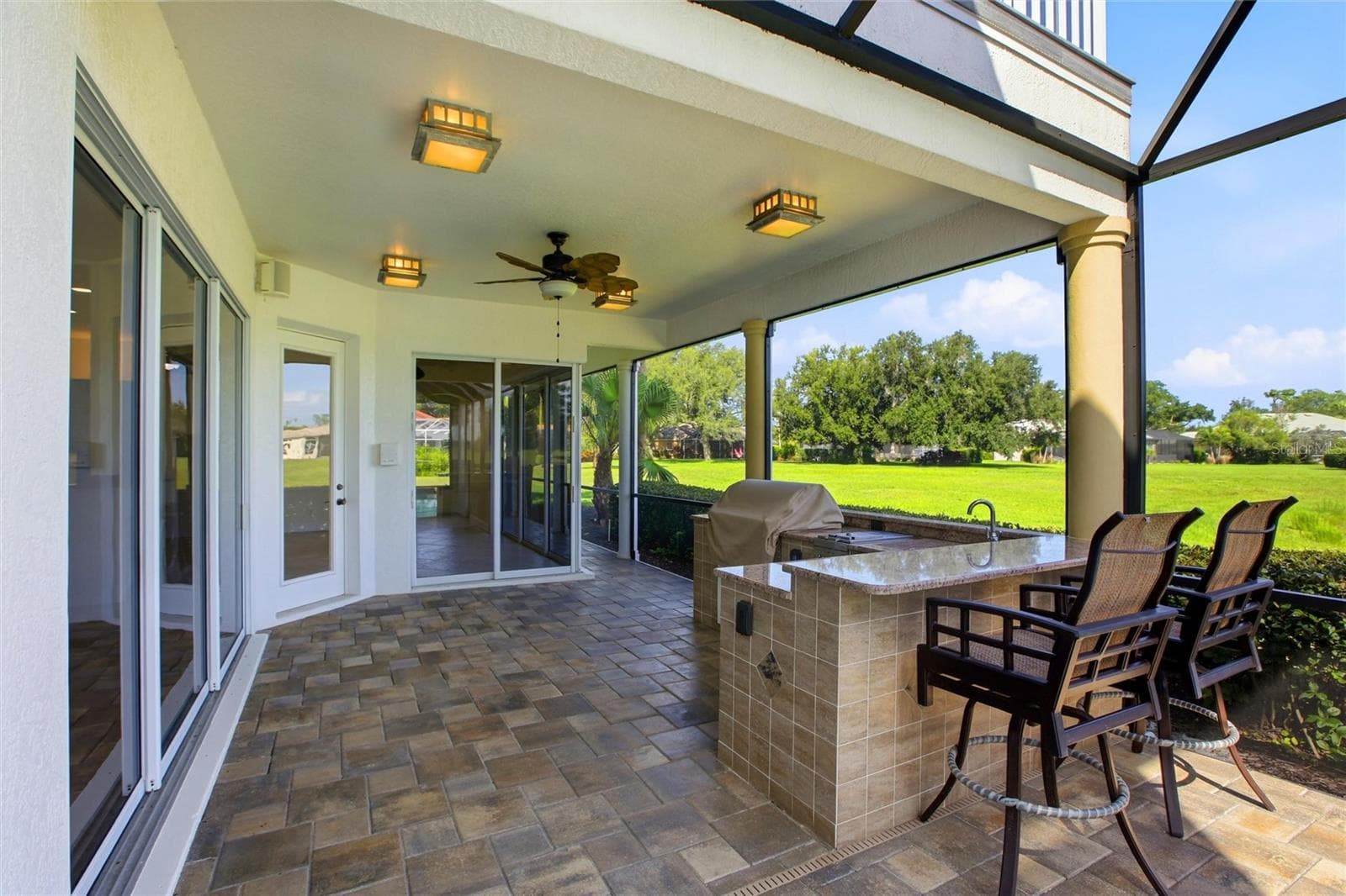 Enjoy resort-style living with a heated pool and spa, plus an outdoor kitchen complete with a gas grill, cooktop, and refrigerator — all set against picturesque golf course and water views with the peaceful backdrop of Misty Creek’s natural beauty and visiting deer. - 8417 LONE EAGLE WAY, SARASOTA