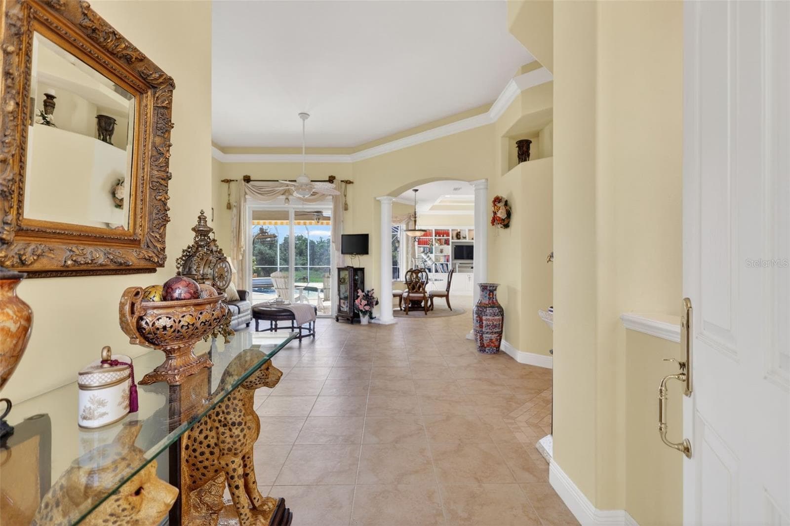 The welcoming foyer introduces the home's open-concept design with soaring 14-foot ceilings, custom architectural details, and seamless sightlines to the outdoor living areas. - 1210 408TH CT E, MYAKKA CITY