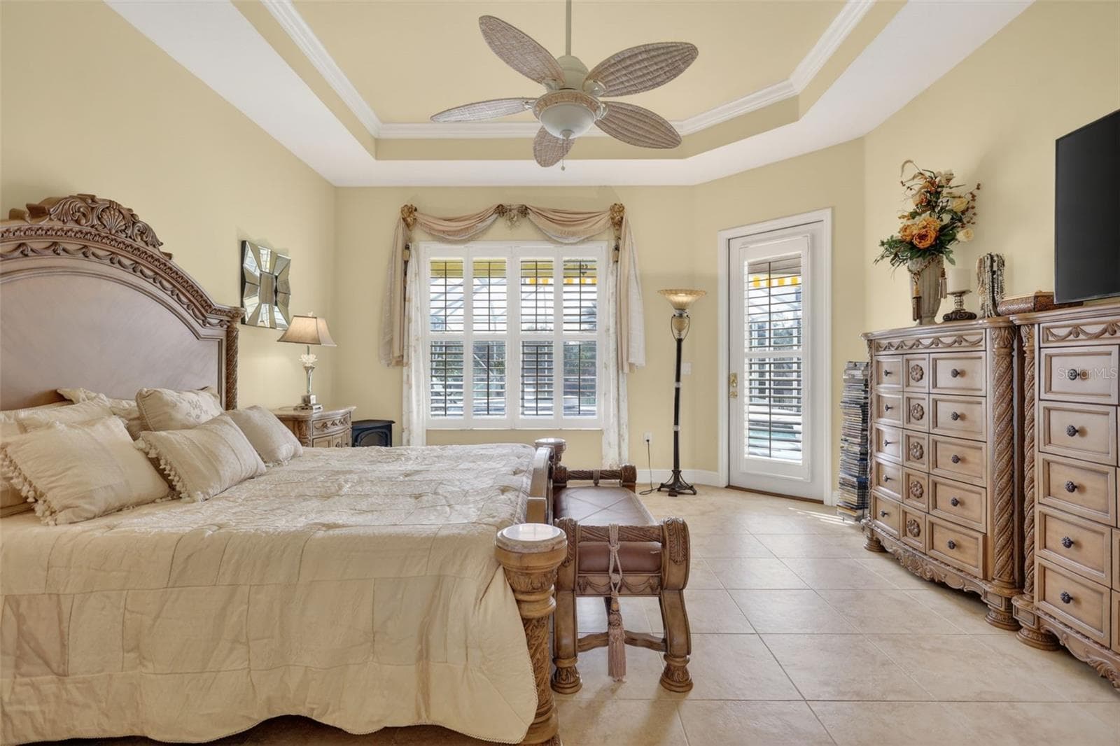 The generously sized primary suite features tray ceilings, plantation shutters, private lanai access, and plenty of room to relax and unwind. - 1210 408TH CT E, MYAKKA CITY