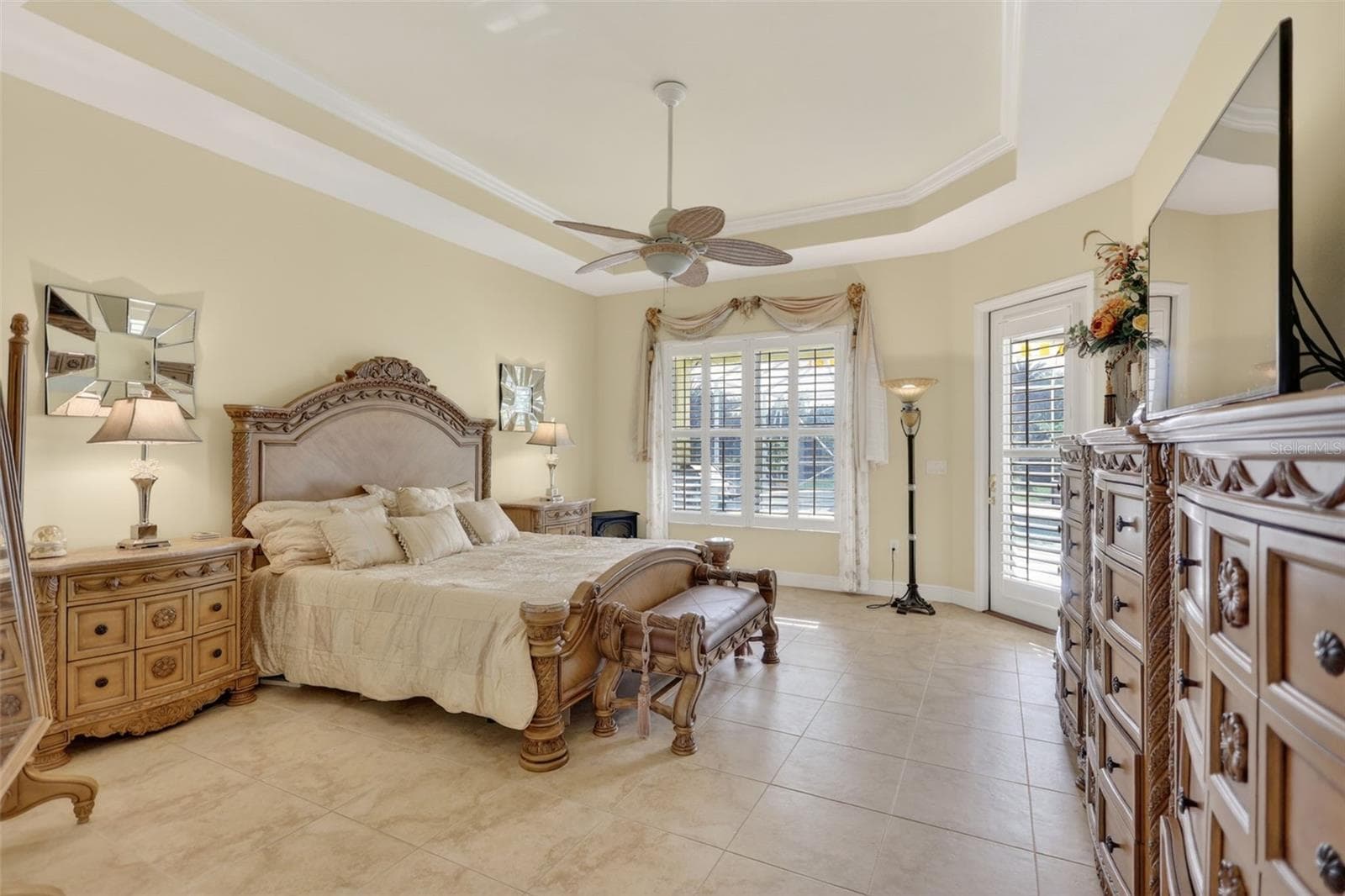 The spacious primary bedroom offers elegant architectural details, abundant natural light, and direct access to the outdoor living area. - 1210 408TH CT E, MYAKKA CITY