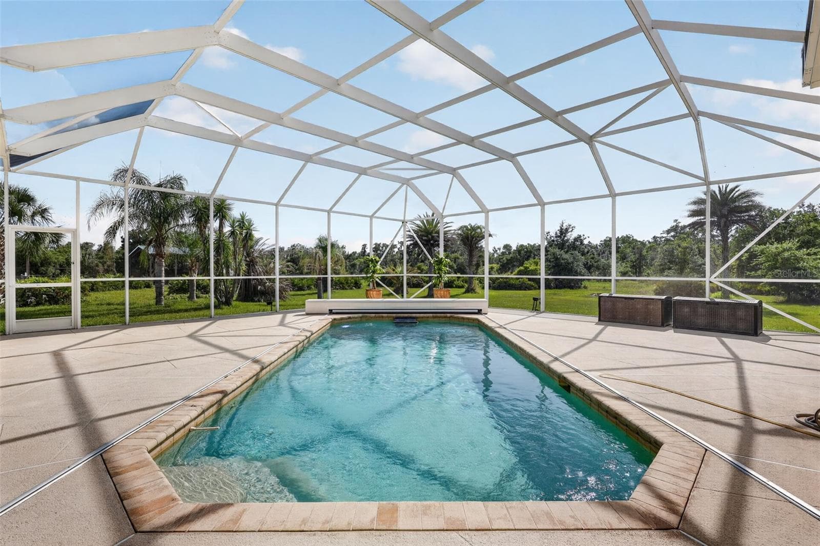 The screened pool enclosure frames picturesque views of the surrounding landscape while providing an exceptional private outdoor retreat. - 1210 408TH CT E, MYAKKA CITY