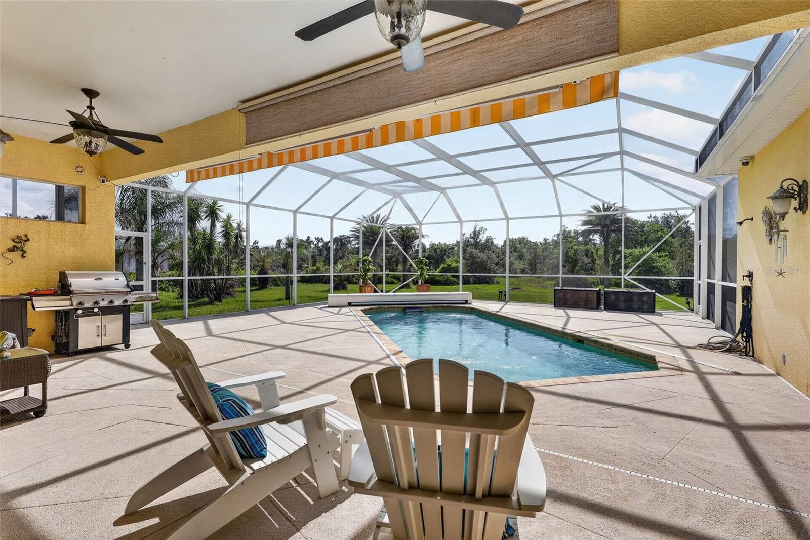 The covered lanai seamlessly blends indoor and outdoor living with generous entertaining space, retractable awnings, ceiling fans, and scenic views beyond. - 1210 408TH CT E, MYAKKA CITY