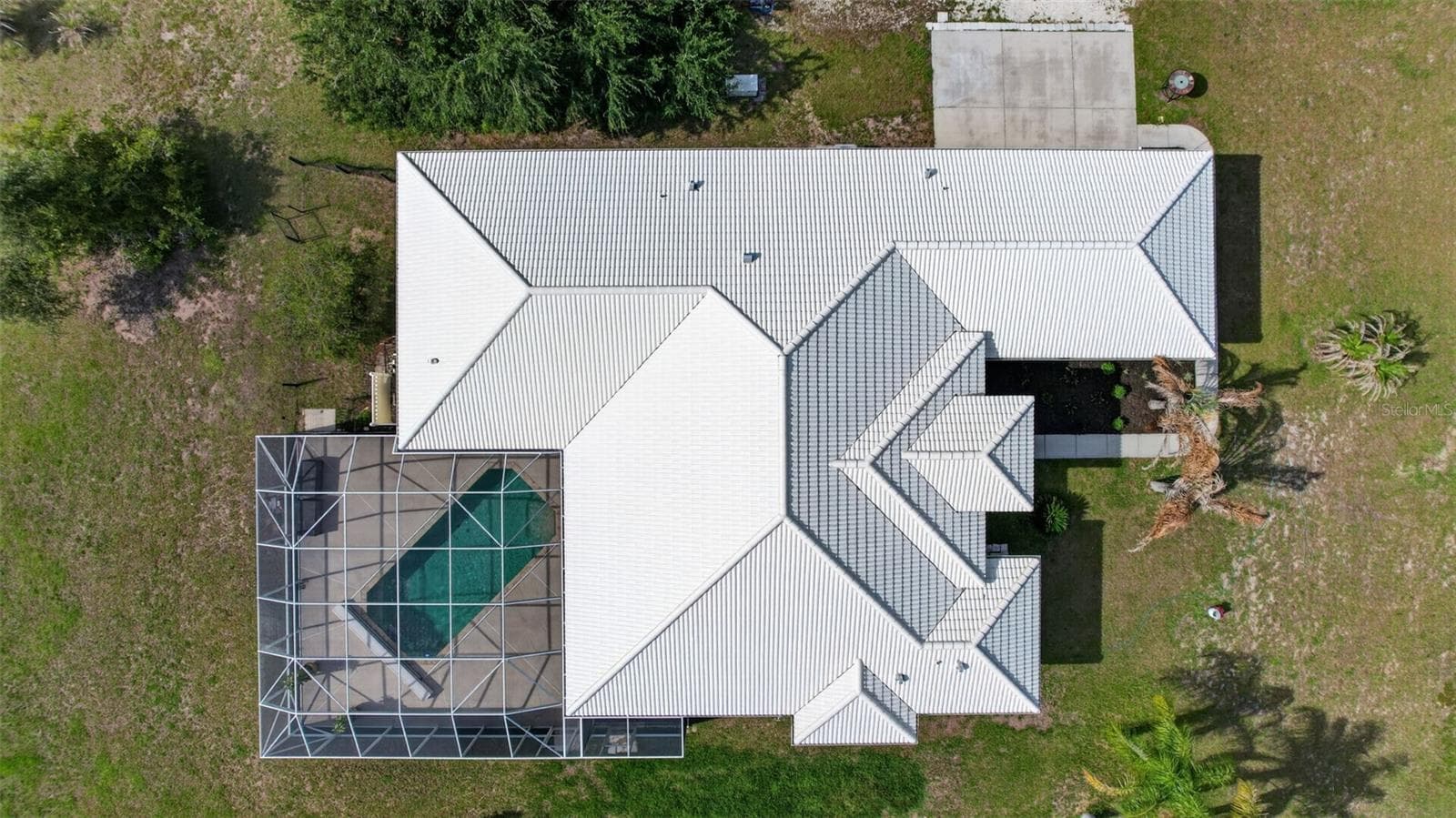 An aerial perspective highlights the home's thoughtfully designed floor plan, expansive screened pool enclosure, and generous acreage setting. - 1210 408TH CT E, MYAKKA CITY