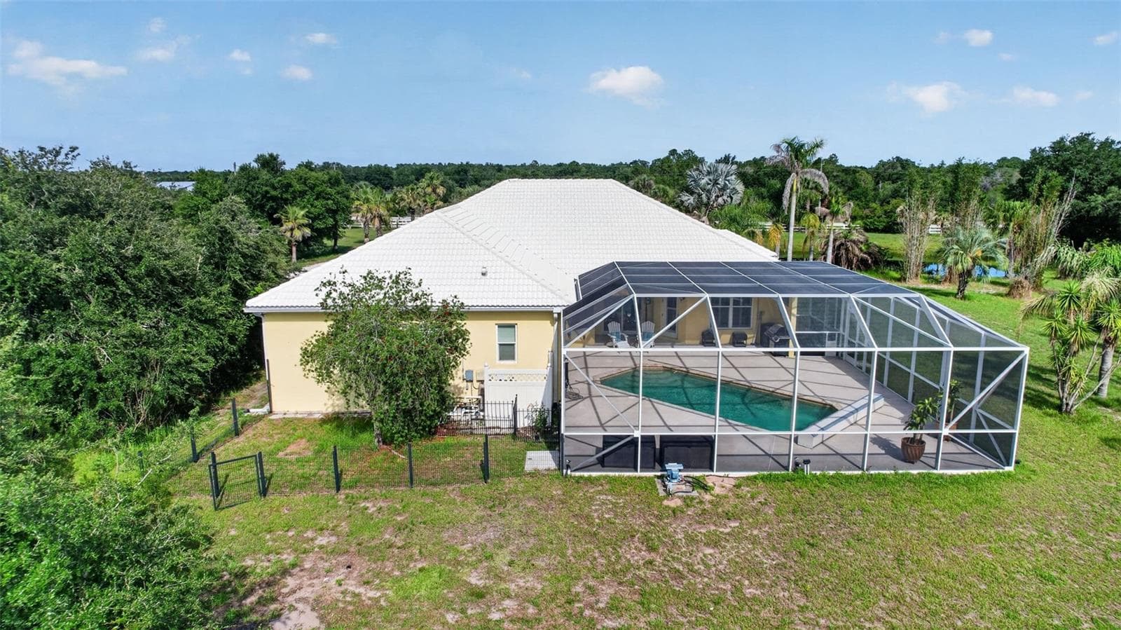 An aerial perspective showcases the expansive screened pool enclosure, adjacent fenced dog run, and the home's exceptional privacy on over six acres. - 1210 408TH CT E, MYAKKA CITY