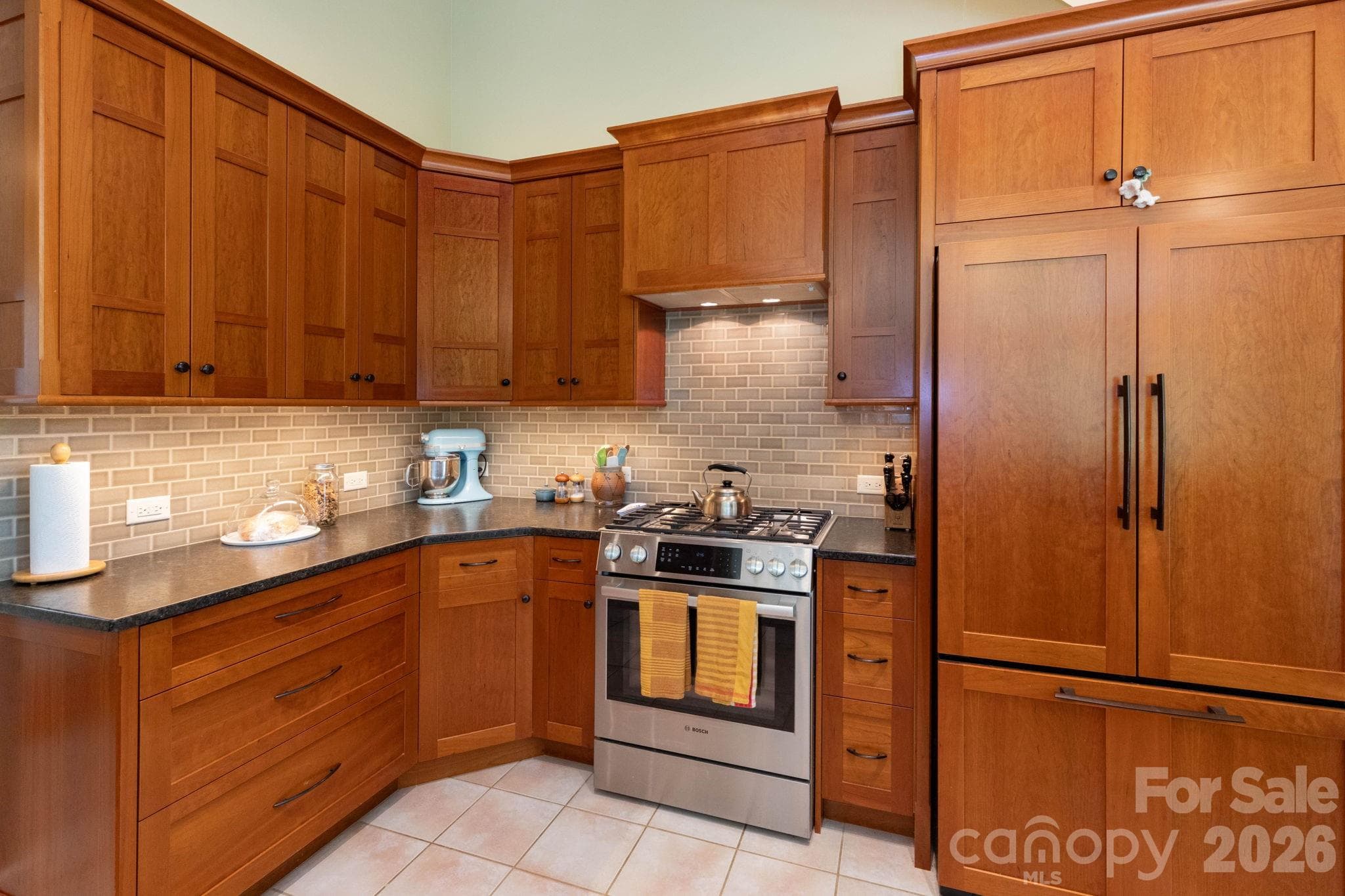 Custom kitchen designed with rich wood cabinetry, tile backsplash, gas range, and thoughtful craftsmanship blending warmth, beauty, and functionality. - 29 Gardner Drive, Asheville