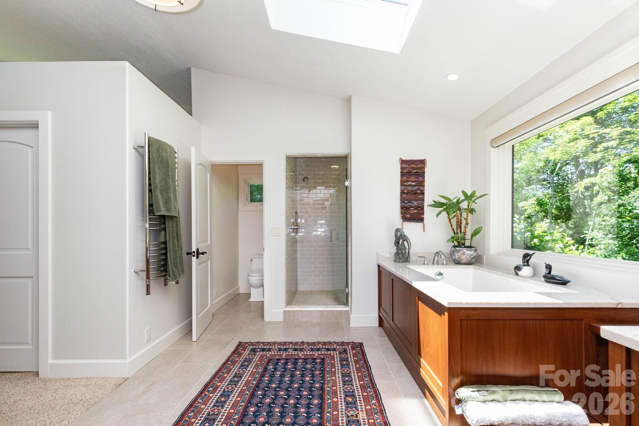 Luxurious primary bath retreat with soaking tub, walk-in tiled shower, and light-filled design creating a calming spa-like experience. - 29 Gardner Drive, Asheville