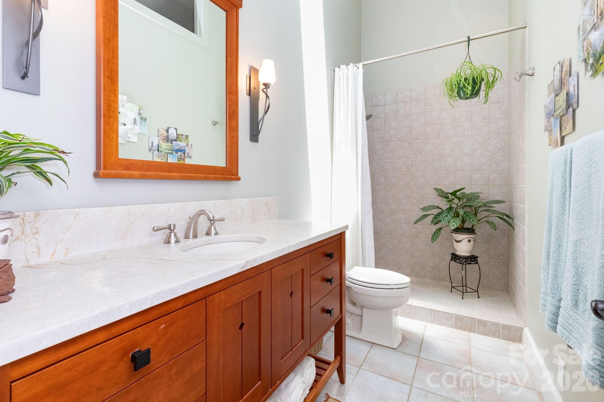 Beautifully appointed bathroom featuring custom wood vanity, solid surface countertops, vaulted ceilings, and a spacious tiled shower with abundant natural light. - 29 Gardner Drive, Asheville