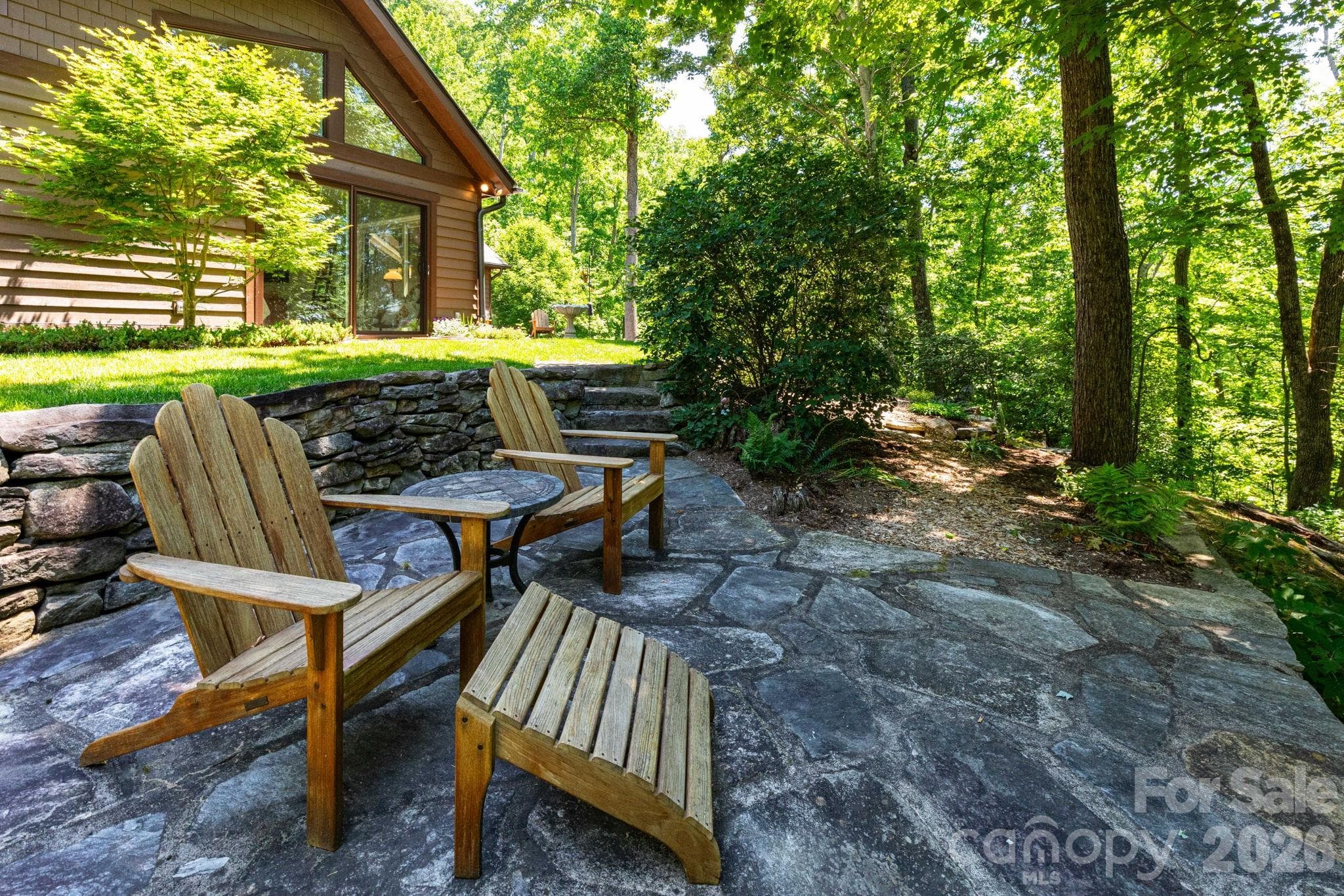 Thoughtfully designed outdoor gathering space with stonework, Adirondack seating, and wooded surroundings creates the perfect setting for quiet mornings or evening conversations. - 29 Gardner Drive, Asheville