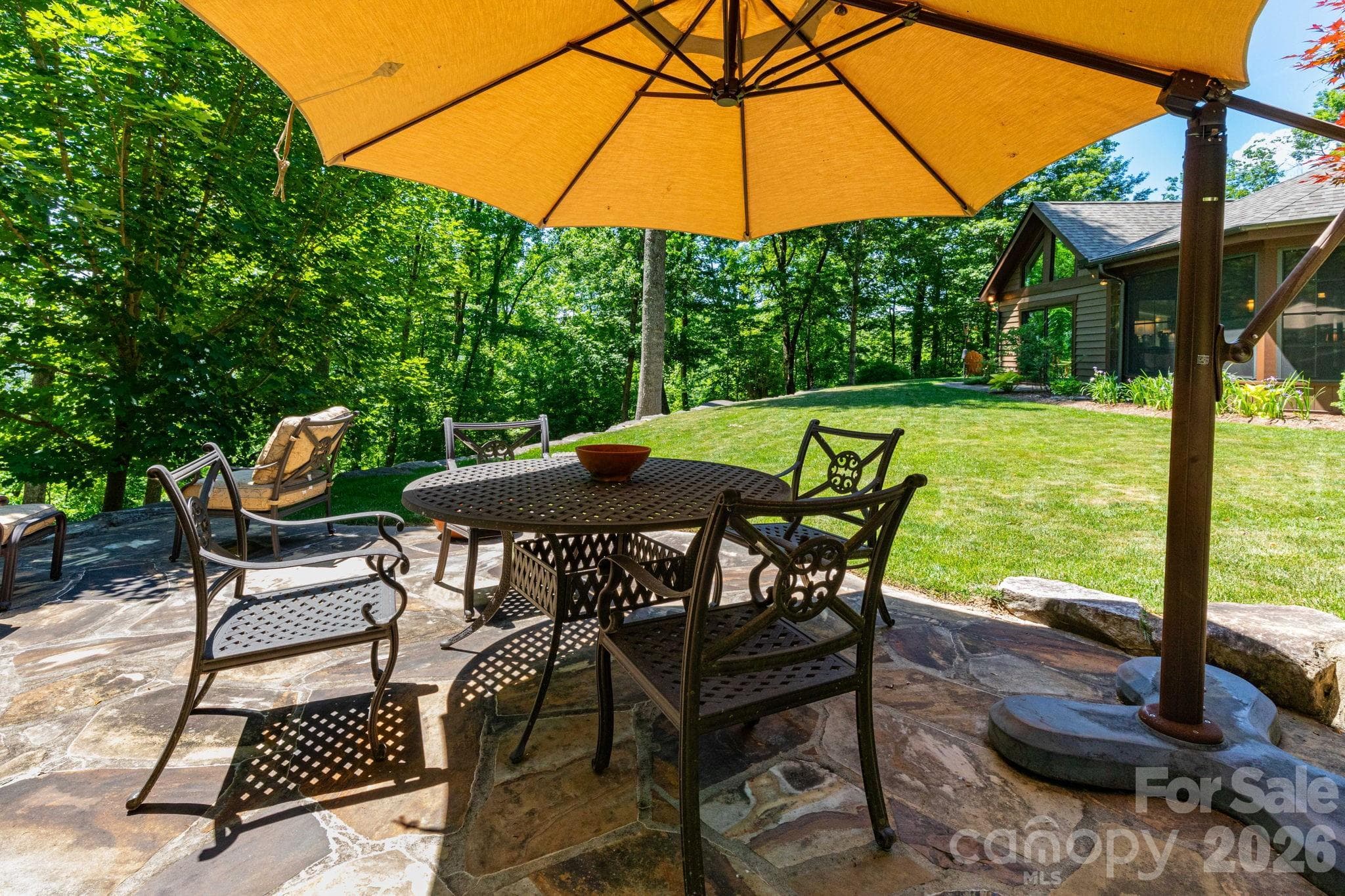 Spacious stone patio with umbrella-covered dining area, ideal for outdoor meals, morning coffee, or evening gatherings. - 29 Gardner Drive, Asheville