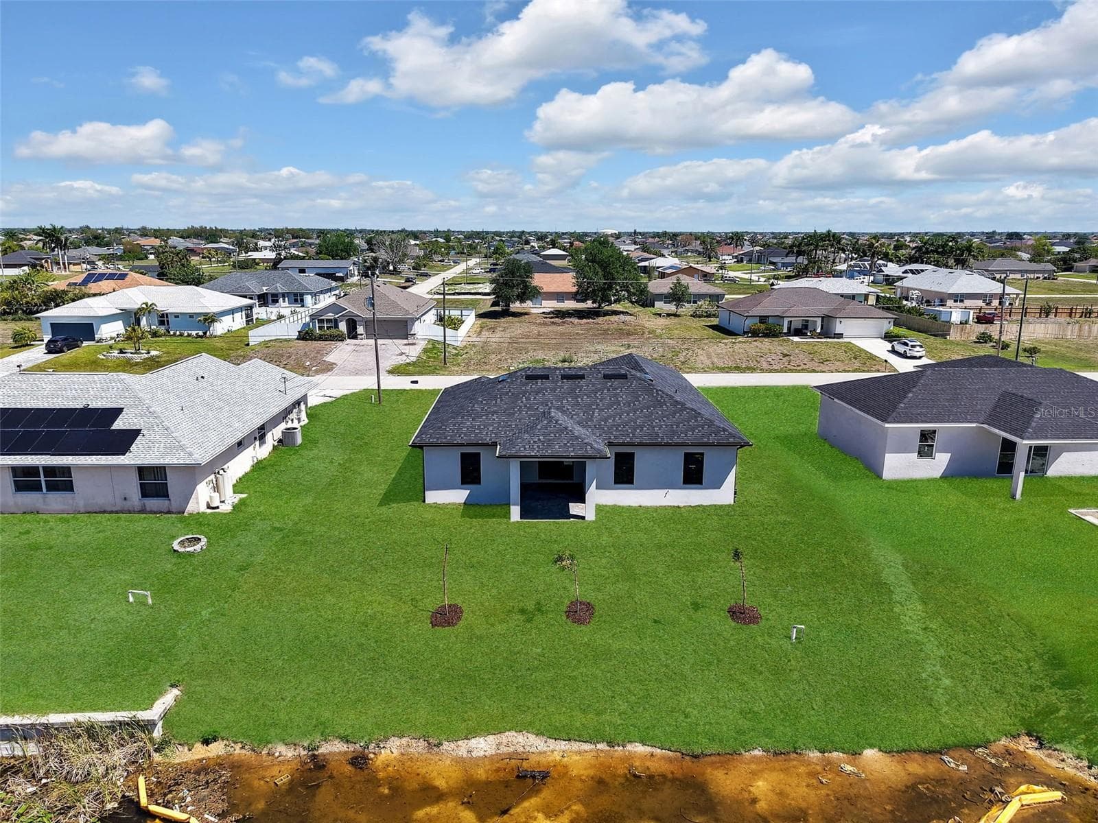 Contemporary-style home featuring a dark shingle roof and a light-colored exterior the color of the grass has been virtually enhanced - 1310 NW 11TH TER, CAPE CORAL