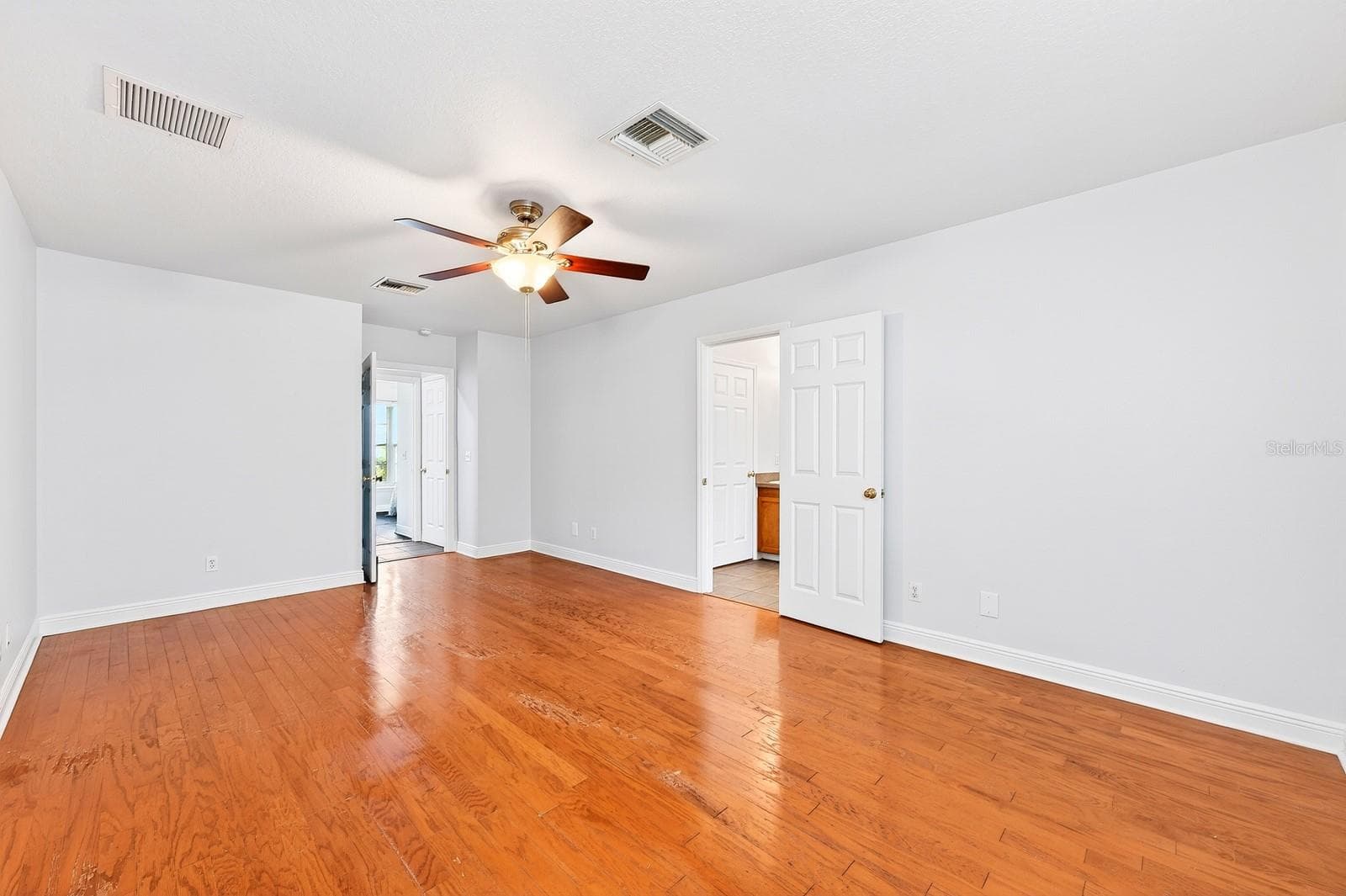 The generous Primary Suite serves as a relaxing retreat, featuring HARDWOOD FLOORING, a sleek ceiling fan, peaceful backyard views, a walk-in closet, and an EN SUITE BATH. - 2706 HARGILL DR, ORLANDO