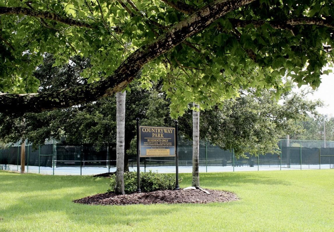 Community tennis courts surrounded by mature trees. - 8601 TWIN FARMS PL, TAMPA