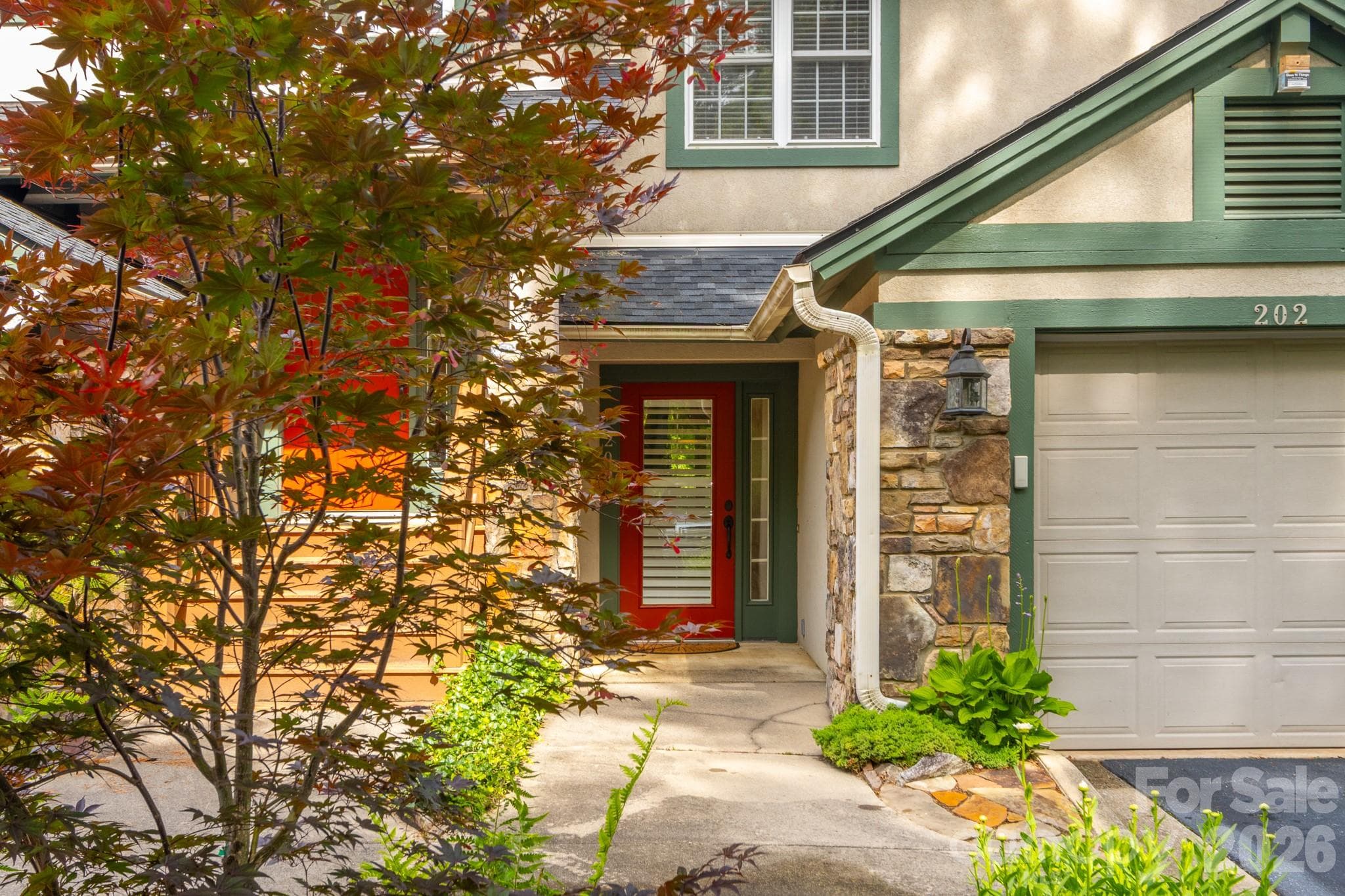 Welcoming Entry Approach – Inviting covered entrance highlighted by beautiful stonework, mature landscaping, and a vibrant entry door creating warm curb appeal. - 99 Ridgetop Circle, Brevard